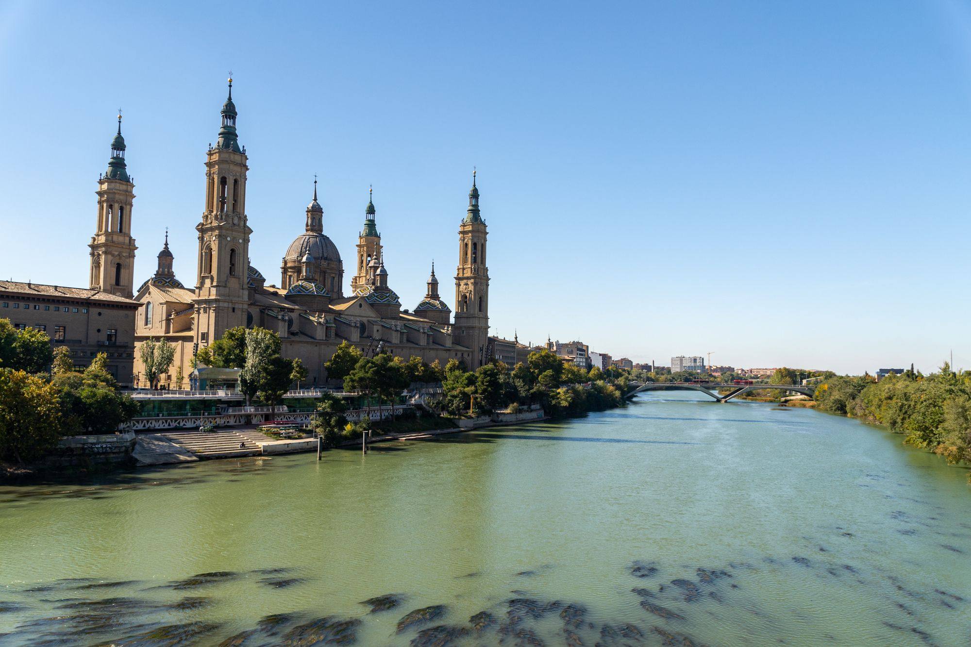 The Basilica of Our Lady of the Pillar on the bank of the Ebro in Zaragoza, with the river in the foreground.