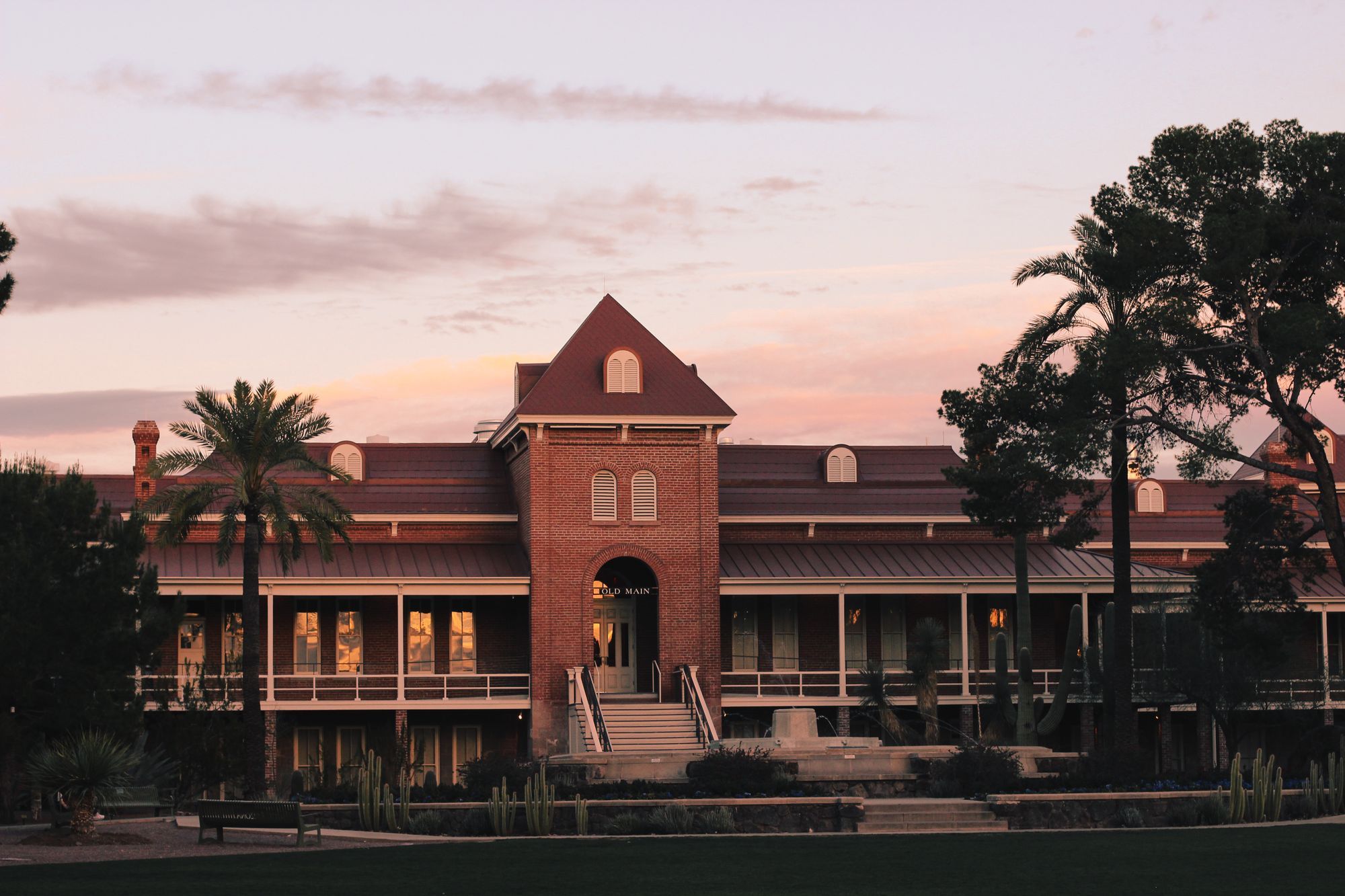 Old Main at the University of Arizona at sunset in Tucson, with palm trees beside it.