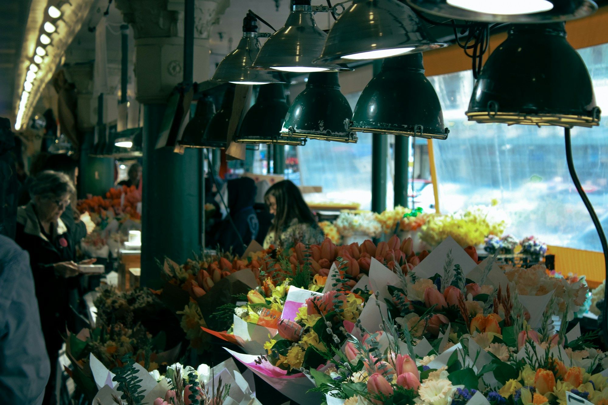 Bunches of flowers for sale under hanging lamps at Pike Place Market in Seattle.