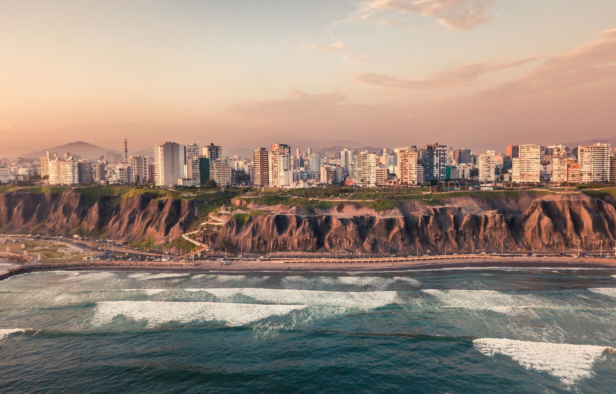 The Miraflores cliffs and the city skyline above the Pacific at sunset in Lima.