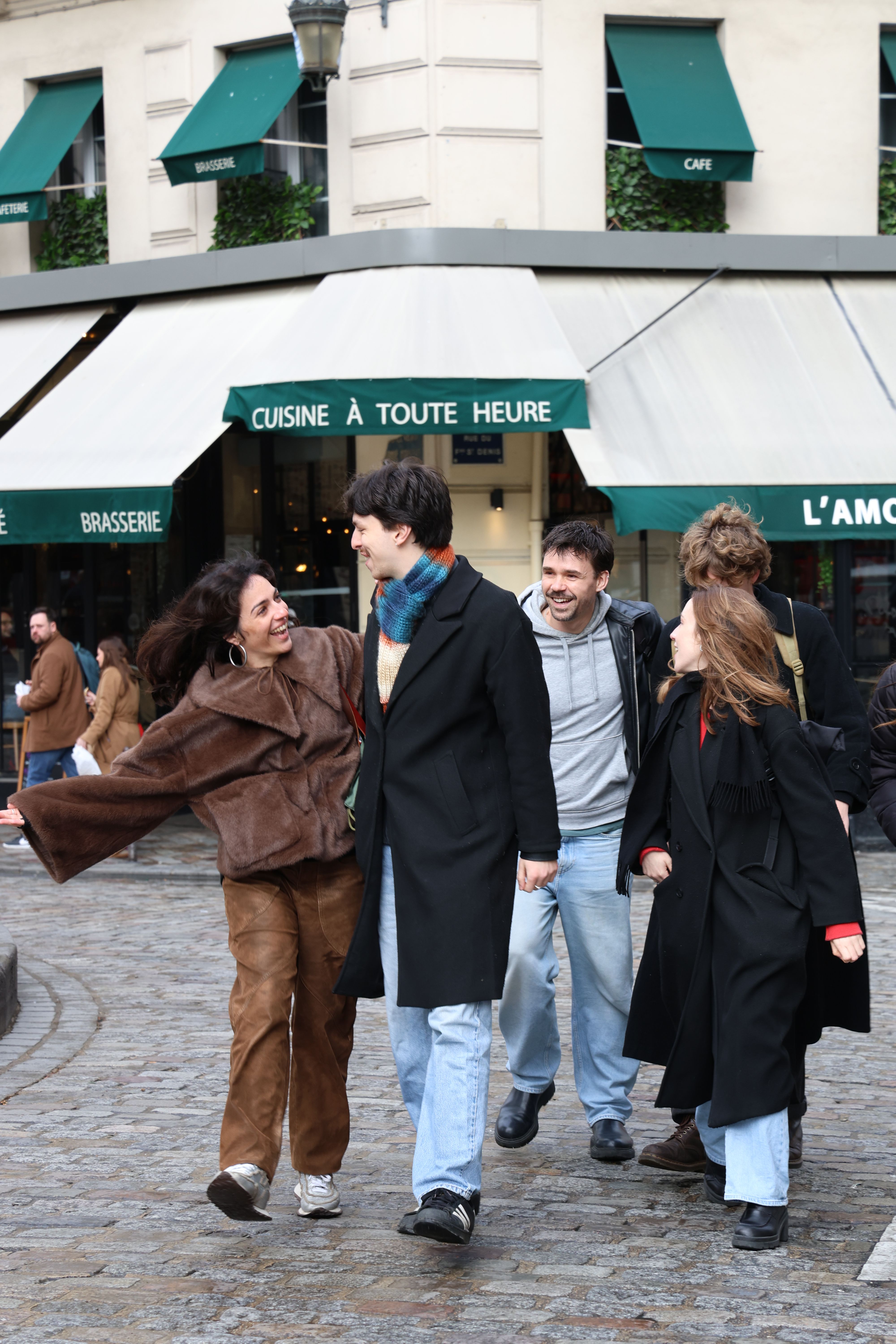 A group walking and laughing across a cobbled street in Paris