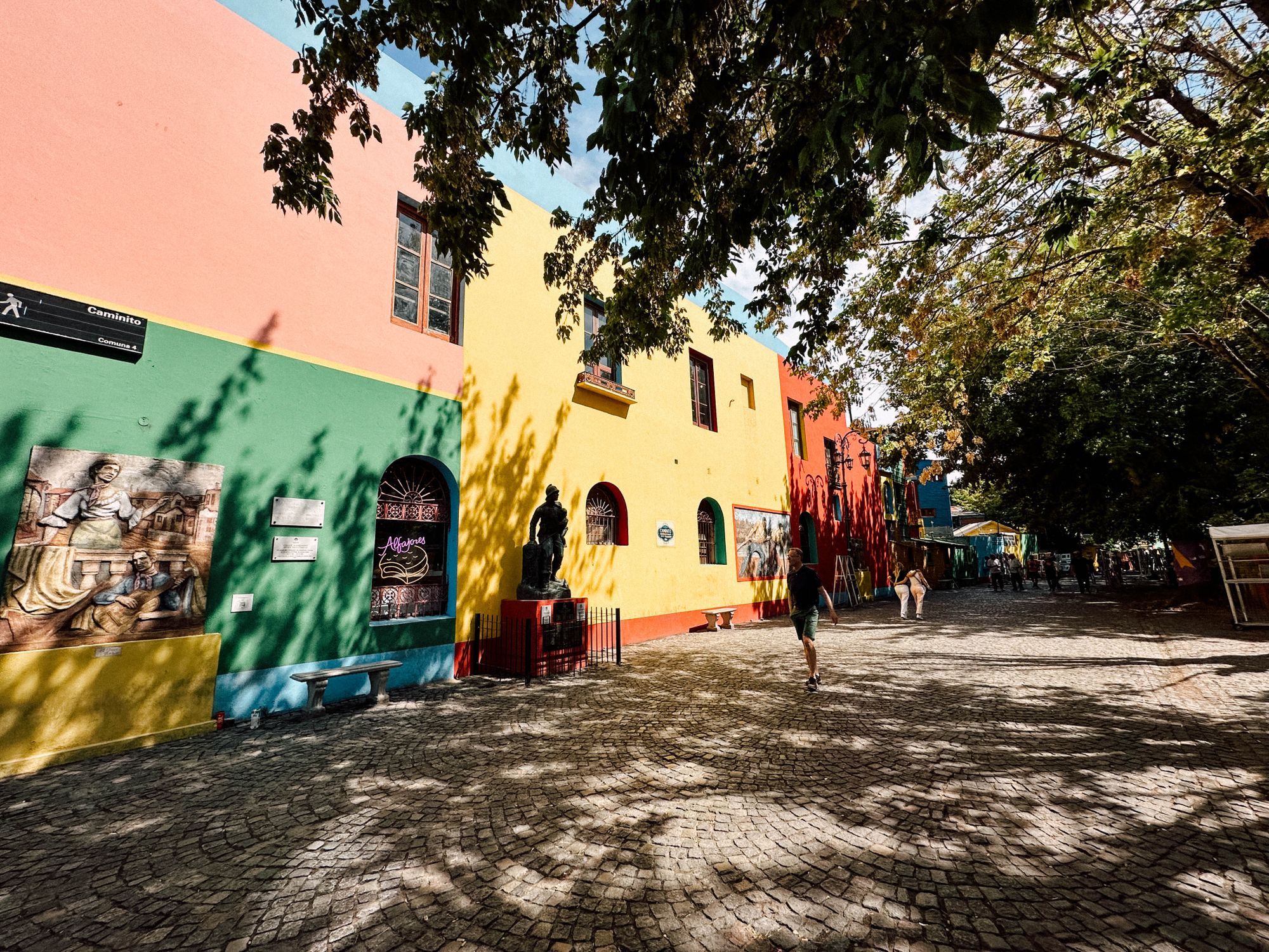 A cobbled lane lined with painted pink, green and yellow walls at Caminito in La Boca, Buenos Aires.