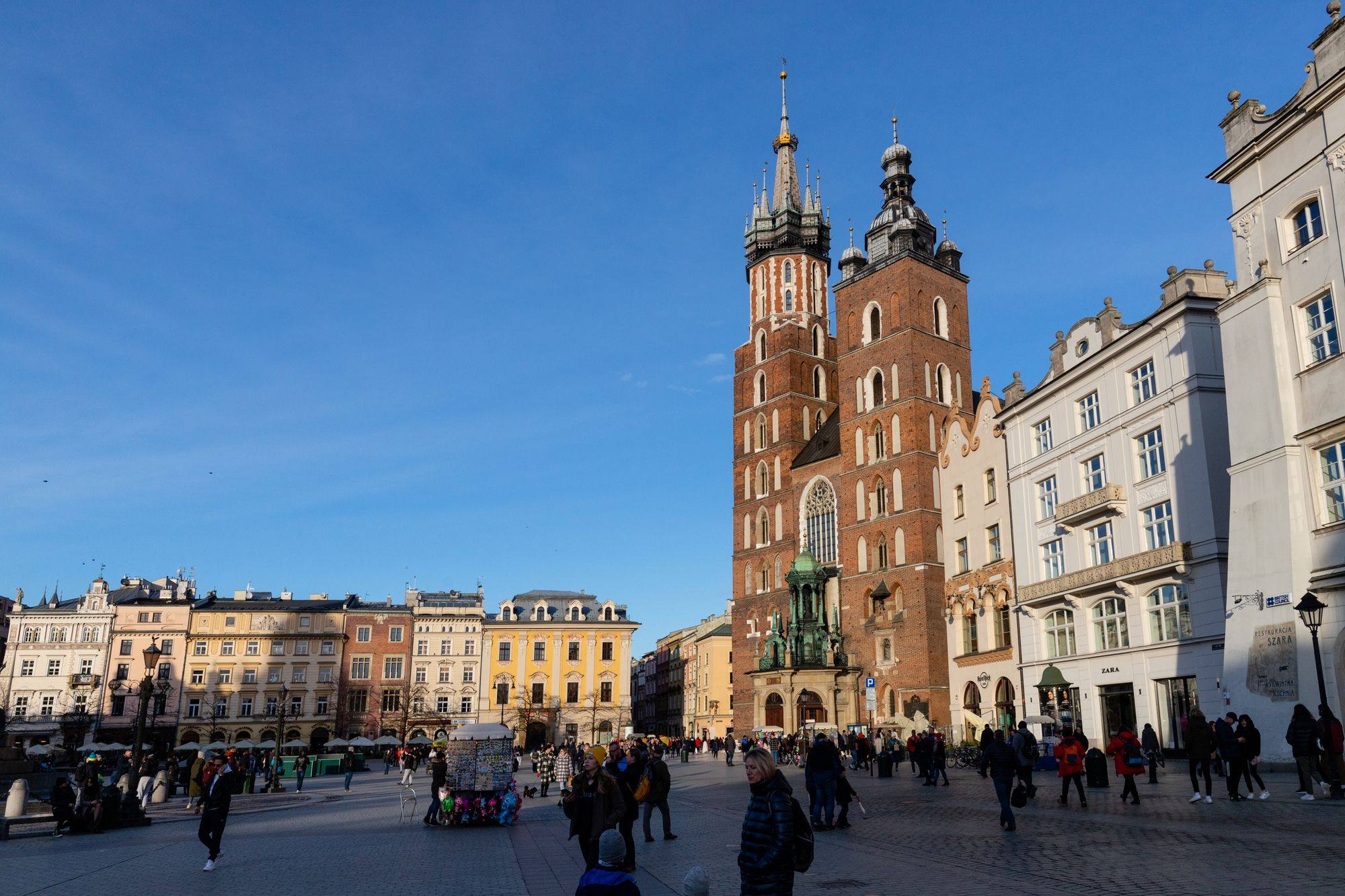 St Mary's Basilica and its two towers on Main Market Square in Kraków, with people on the square.