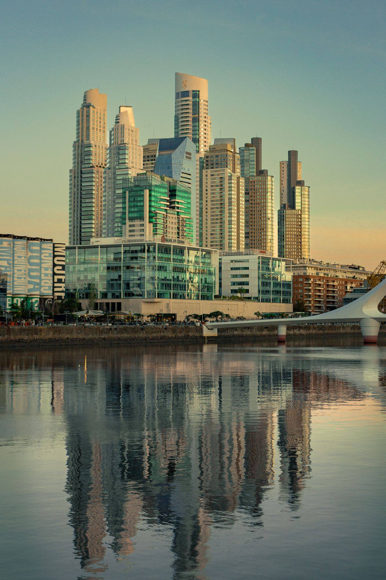 The skyscrapers of Puerto Madero rising above the water of the old docks in Buenos Aires, at golden hour.