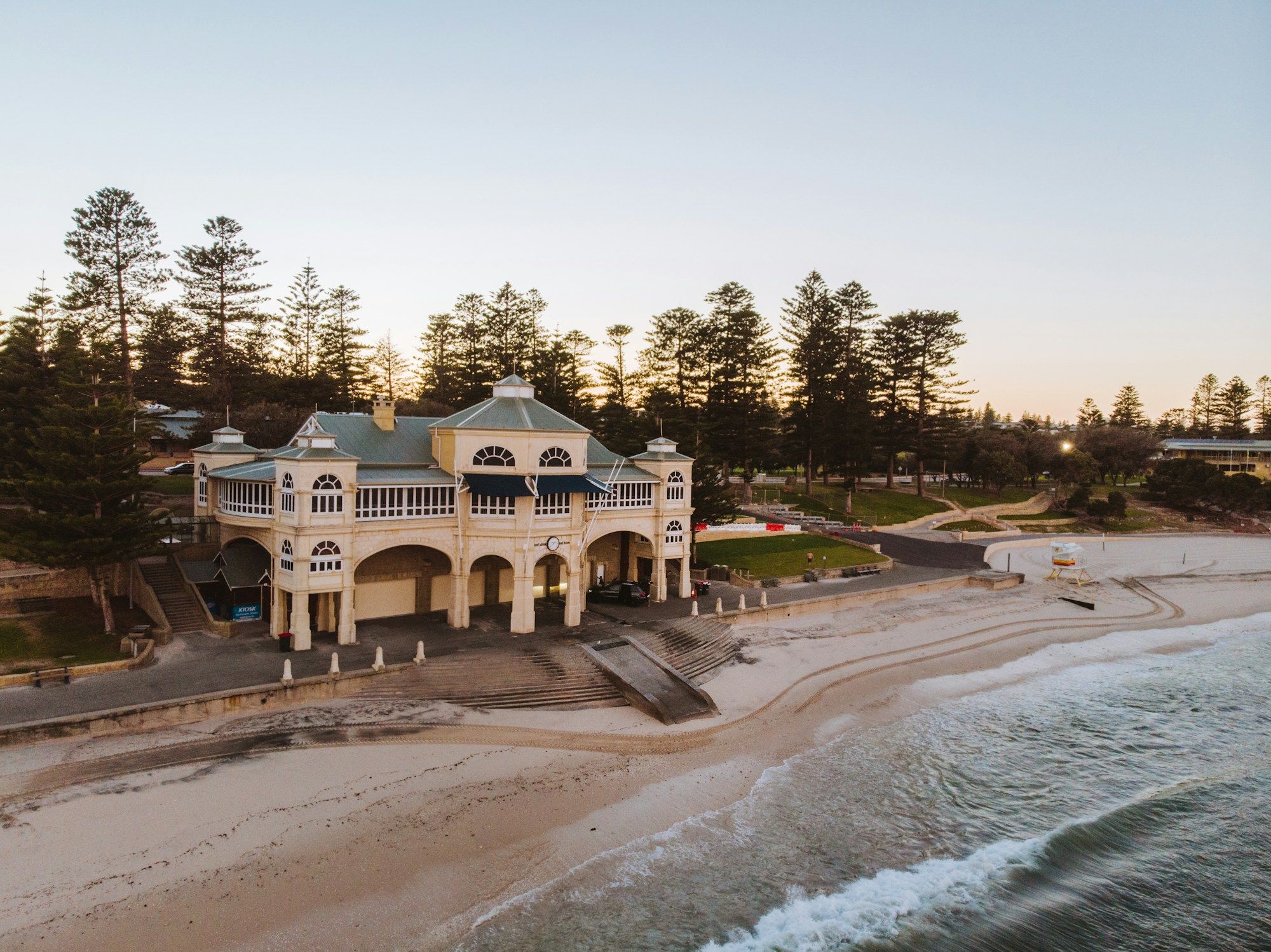 The Indiana Tea House on Cottesloe Beach in Perth, with Norfolk pines behind it and surf on the sand.
