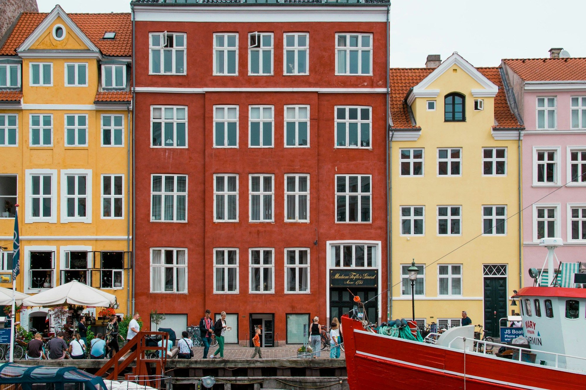 The red and yellow houses of Nyhavn in Copenhagen with people along the quay