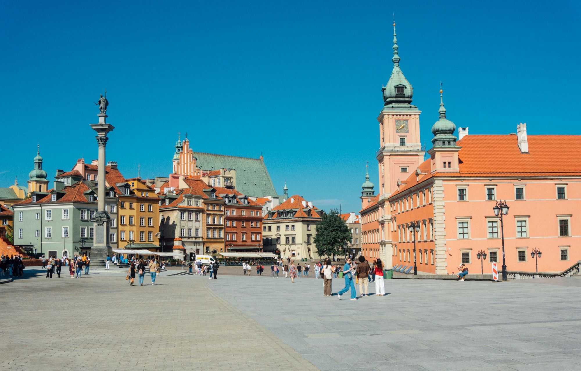 The Royal Castle tower and Sigismund's Column on Castle Square in Warsaw's Old Town, with the paved square in front.