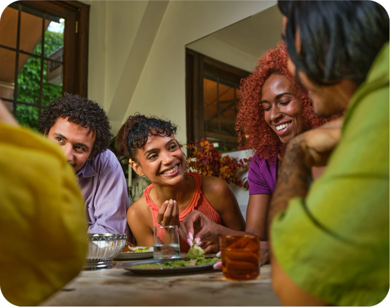 A group of people laughing together over dinner at a Timeleft table