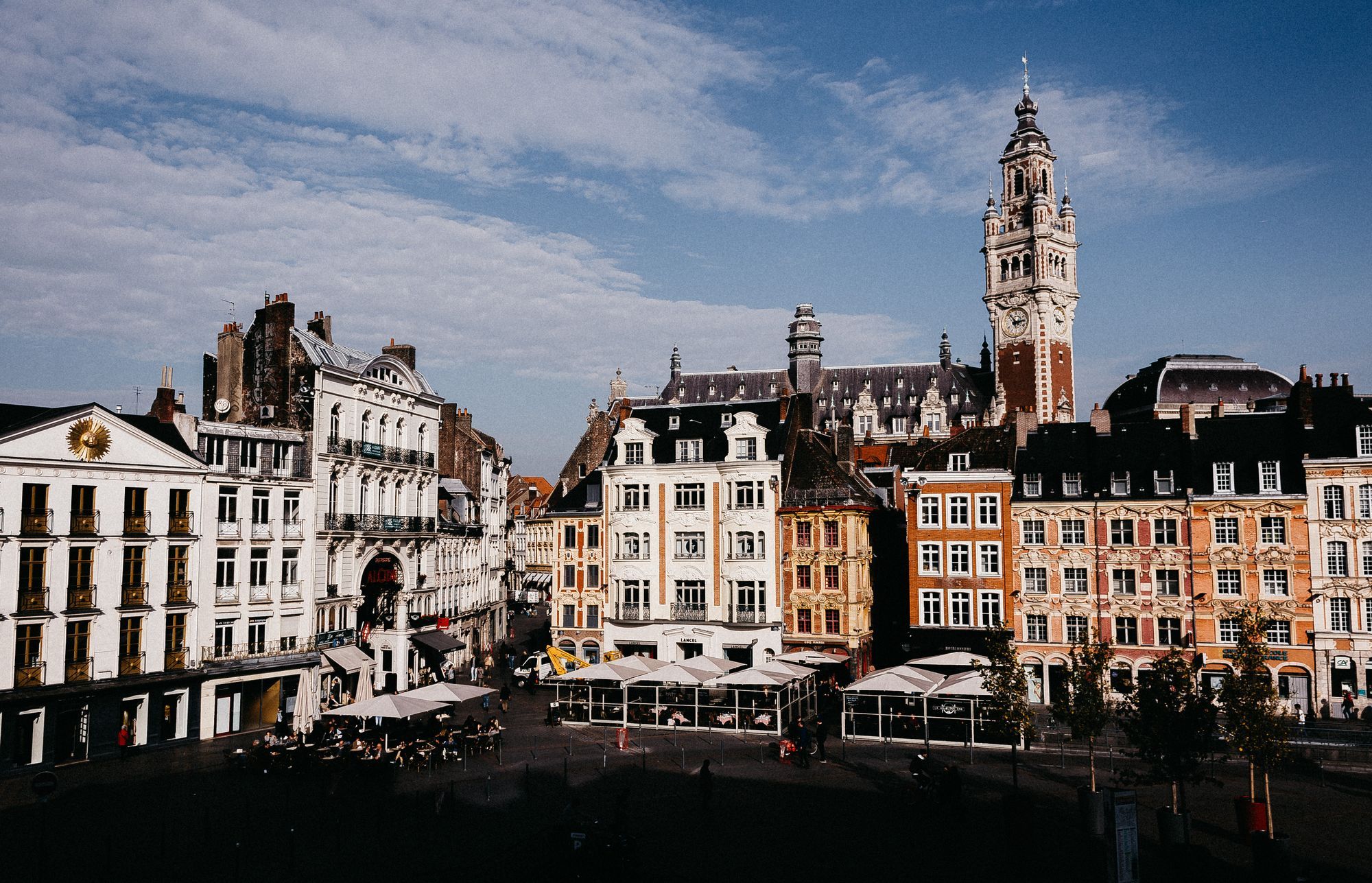 The Grand'Place in Lille with its colorful facades, cafe terraces and the Chambre de Commerce belfry.