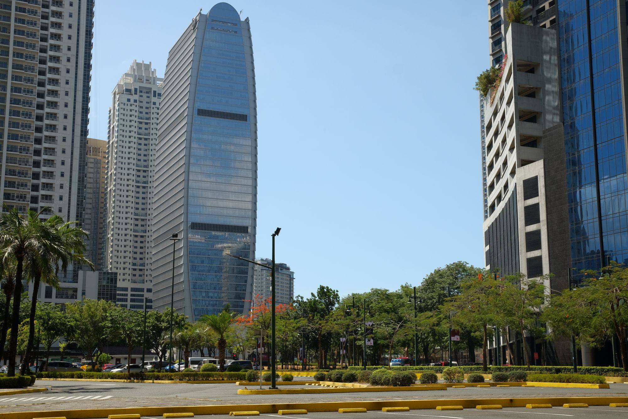 Glass office towers rising above a tree-lined avenue in Bonifacio Global City in Taguig.