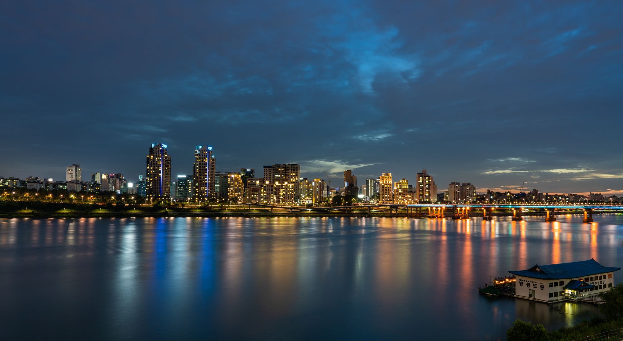 The Seoul skyline at twilight, with city lights reflected in the Han River.