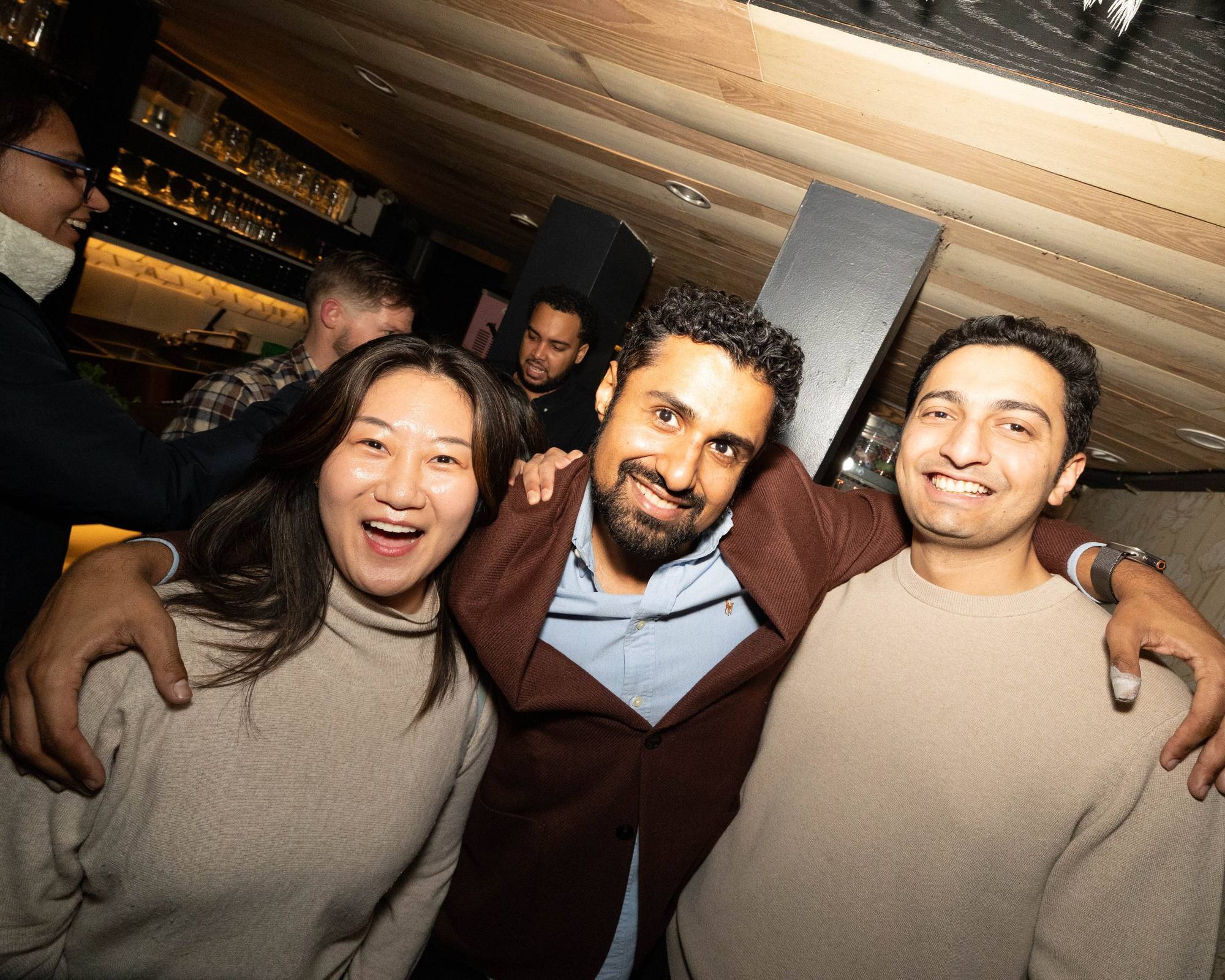 Three friends hugging and grinning at a Timeleft bar evening