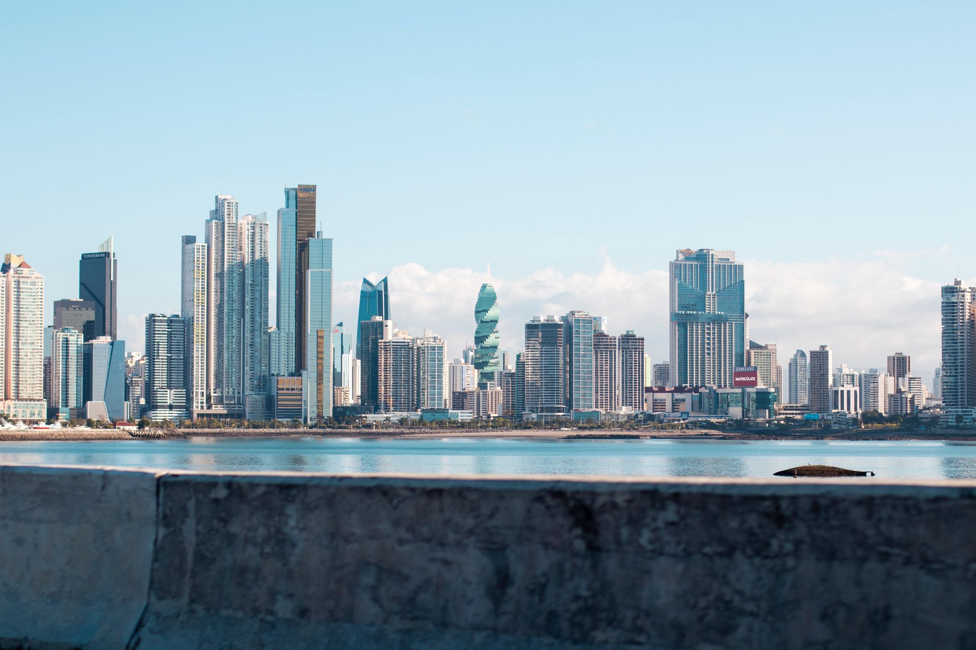 The Panama City skyline across the bay, seen over a sea wall.