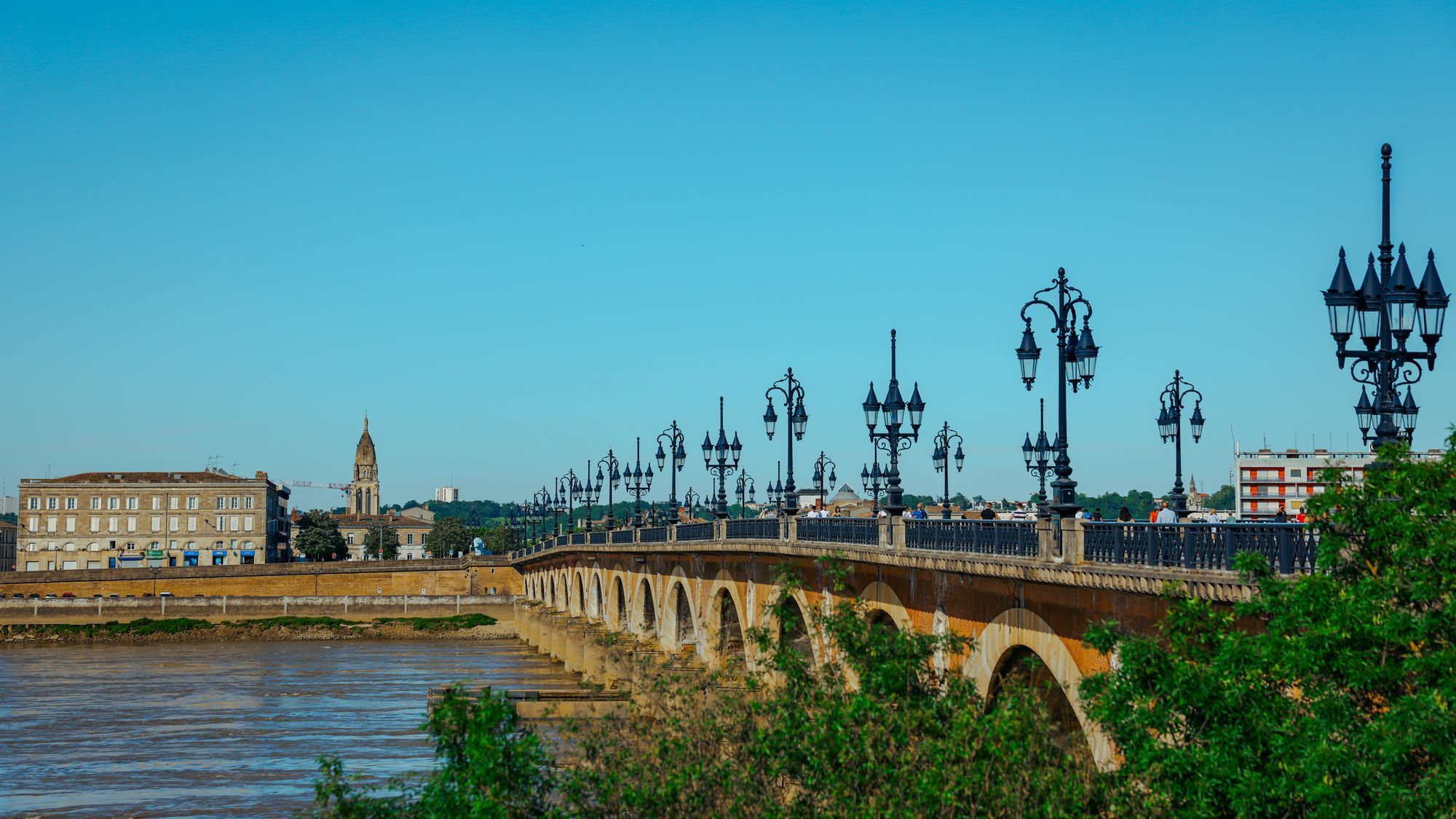 The Pont de Pierre over the Garonne in Bordeaux, with its row of lamp posts under a blue sky.