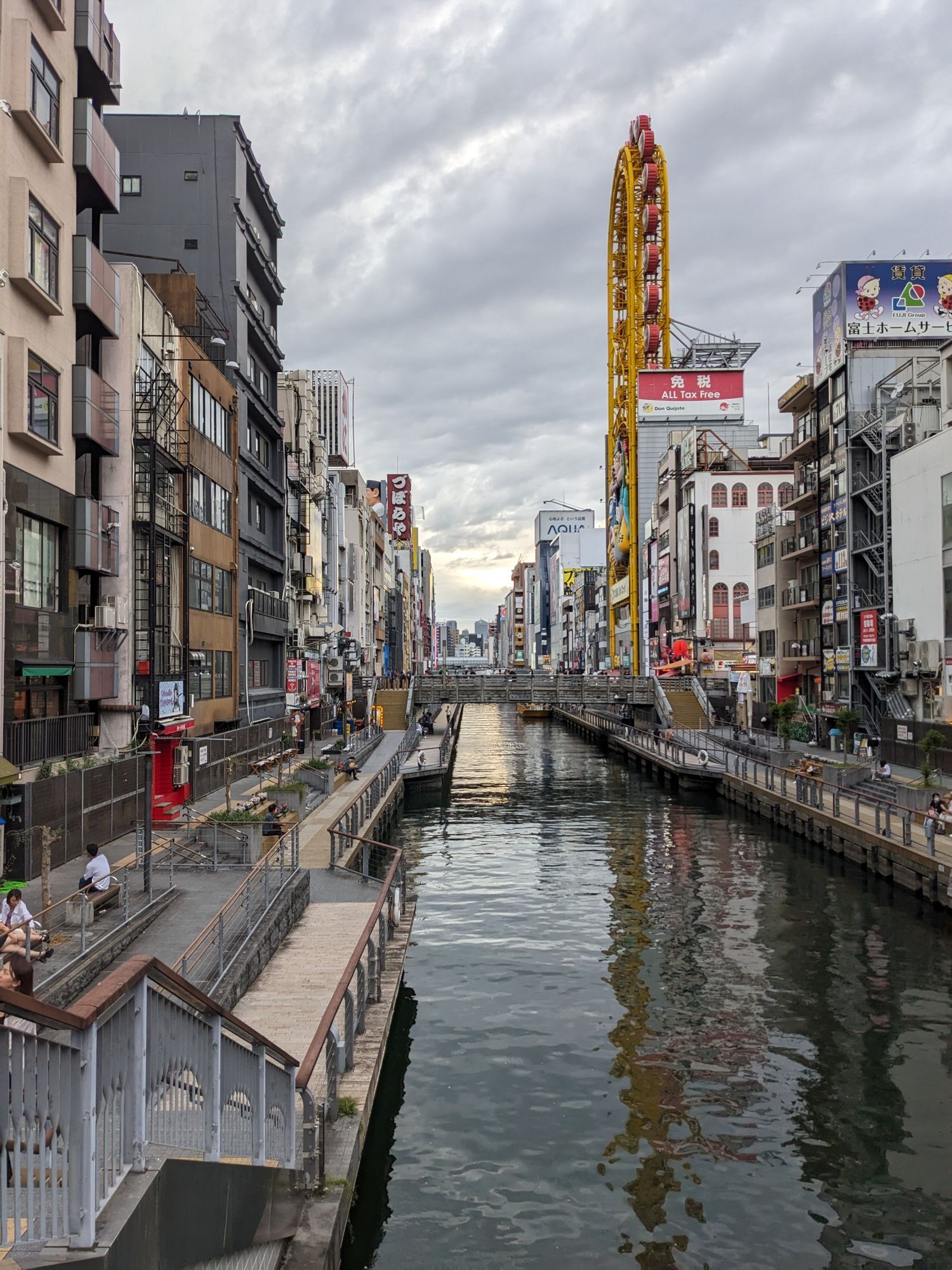 The Dotonbori canal in Osaka seen from a bridge, with shops on both banks.