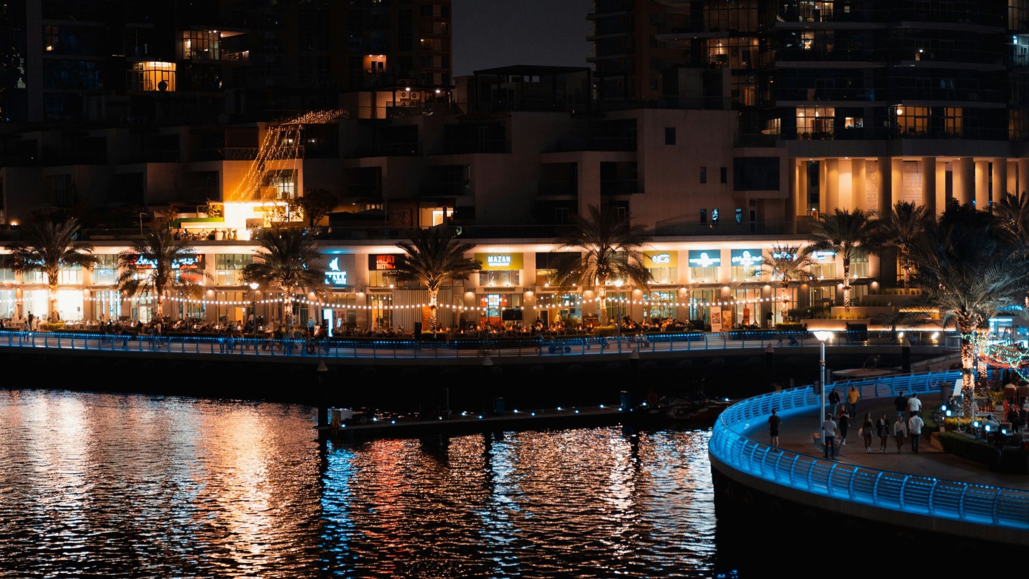 The Dubai Marina promenade at night, beside the water and lit towers