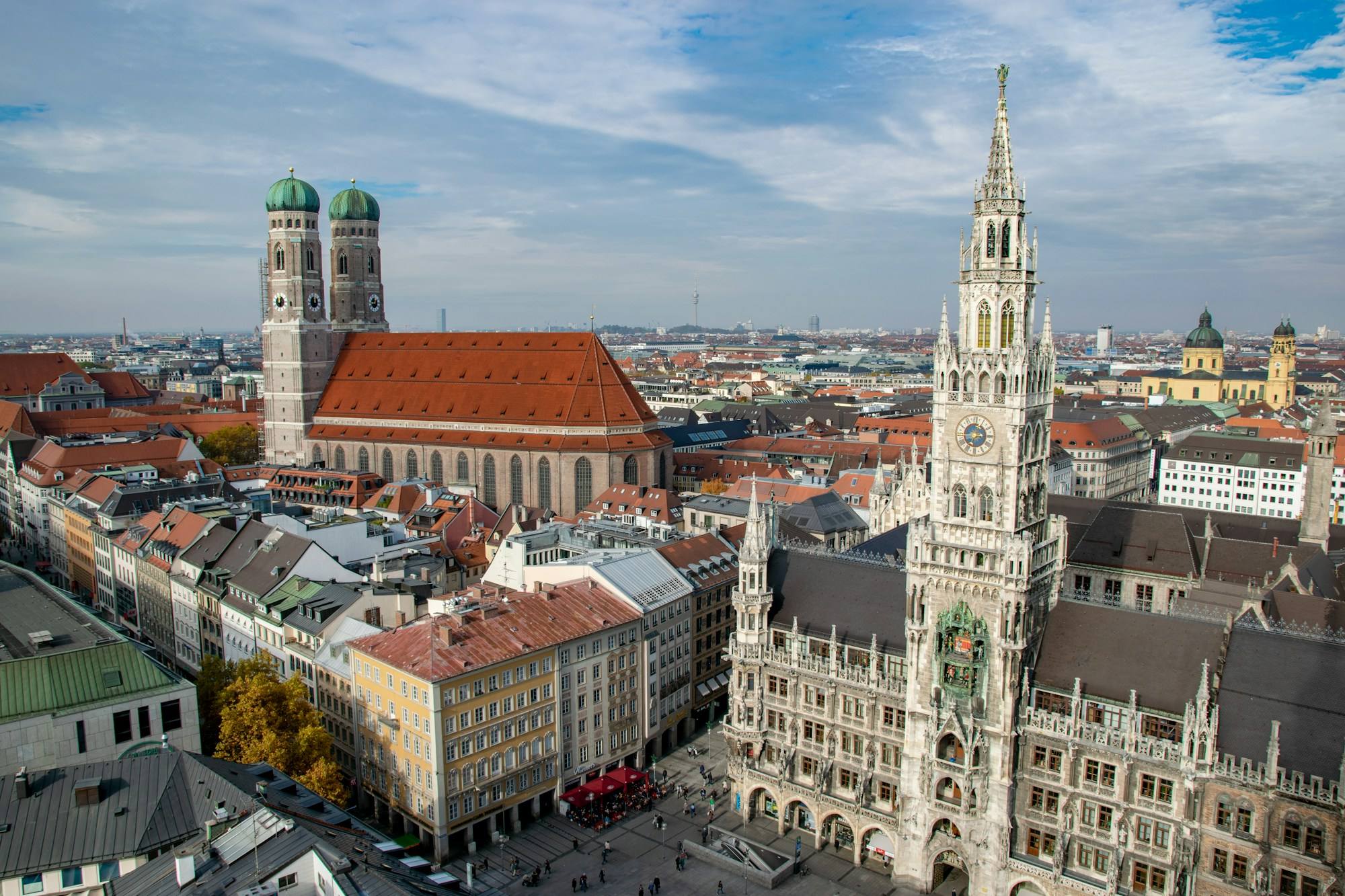 The twin towers of the Frauenkirche and the town hall tower above Marienplatz in Munich, seen from above on a sunny day.