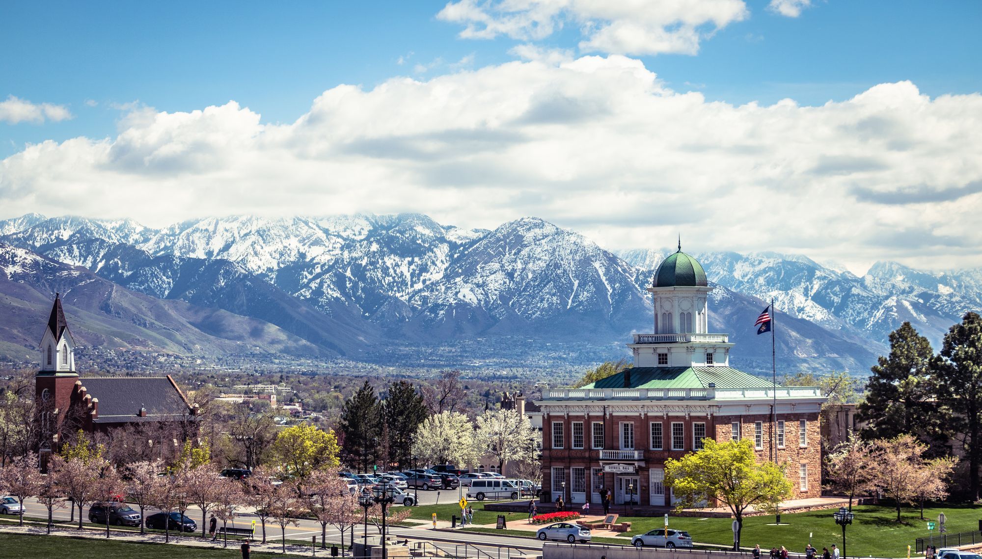 The snow-covered Wasatch Mountains behind a domed building and a church spire in Salt Lake City.