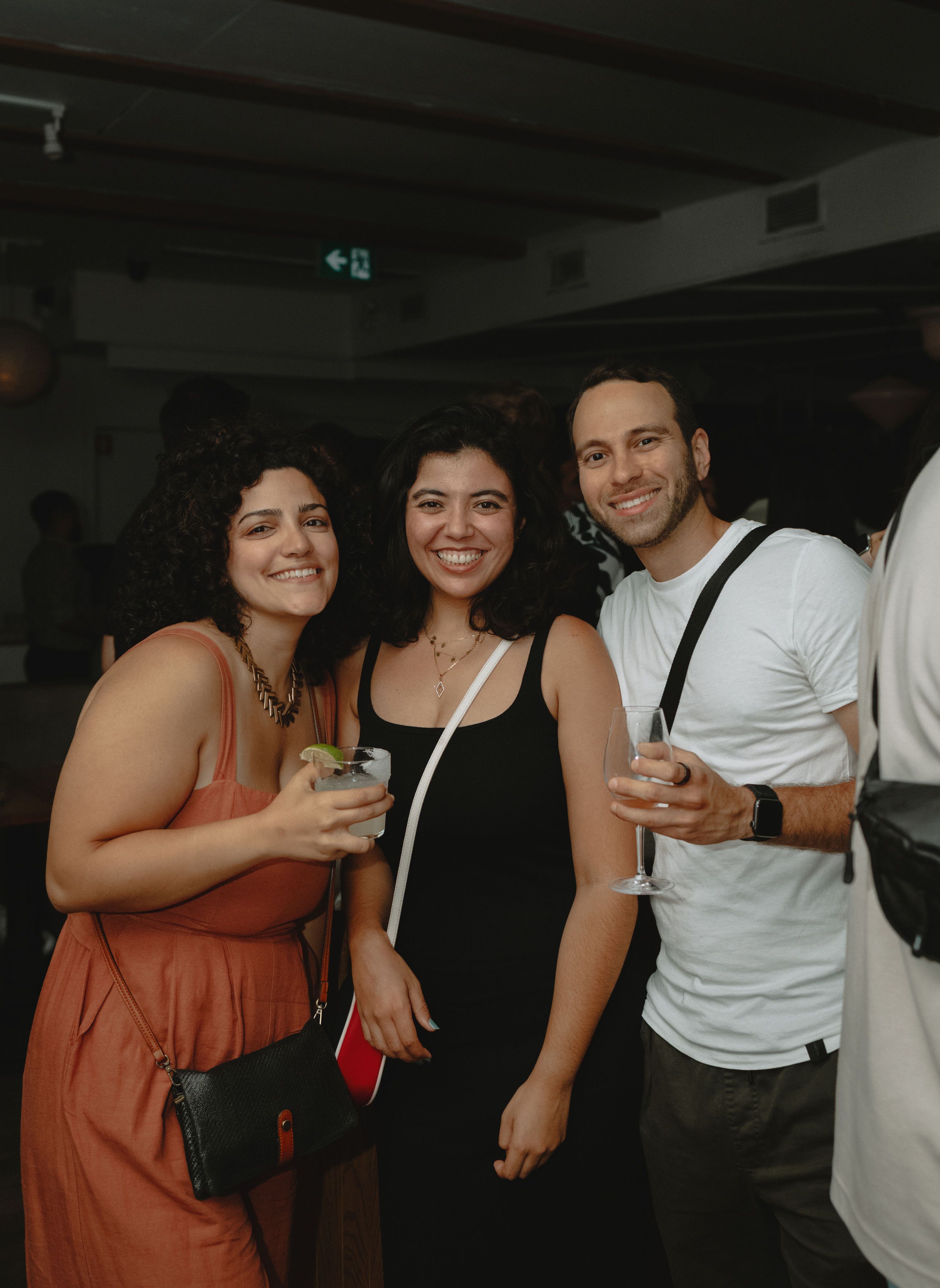 Three people smiling together at an evening event