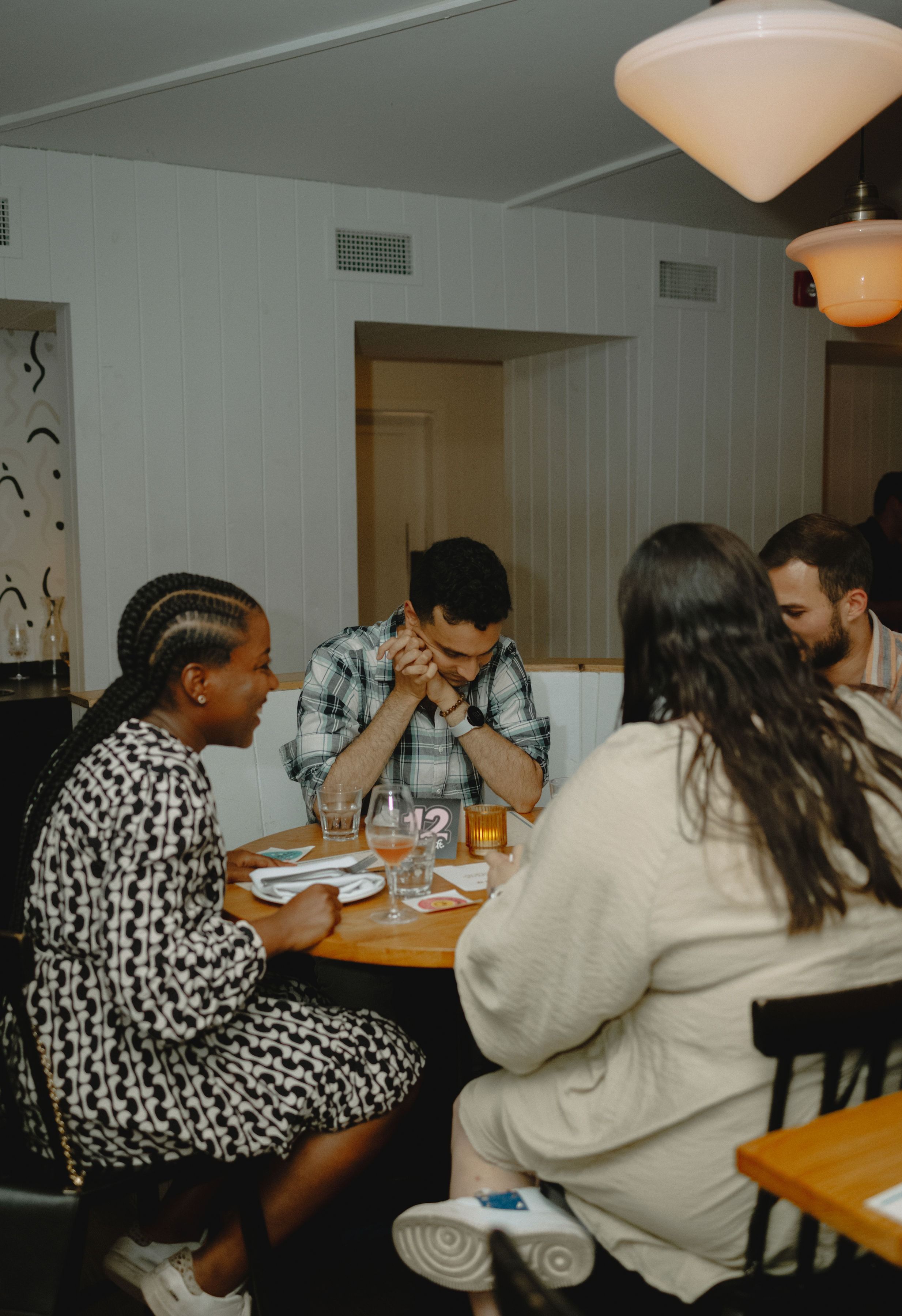 Four people laughing around a small round table on an evening out
