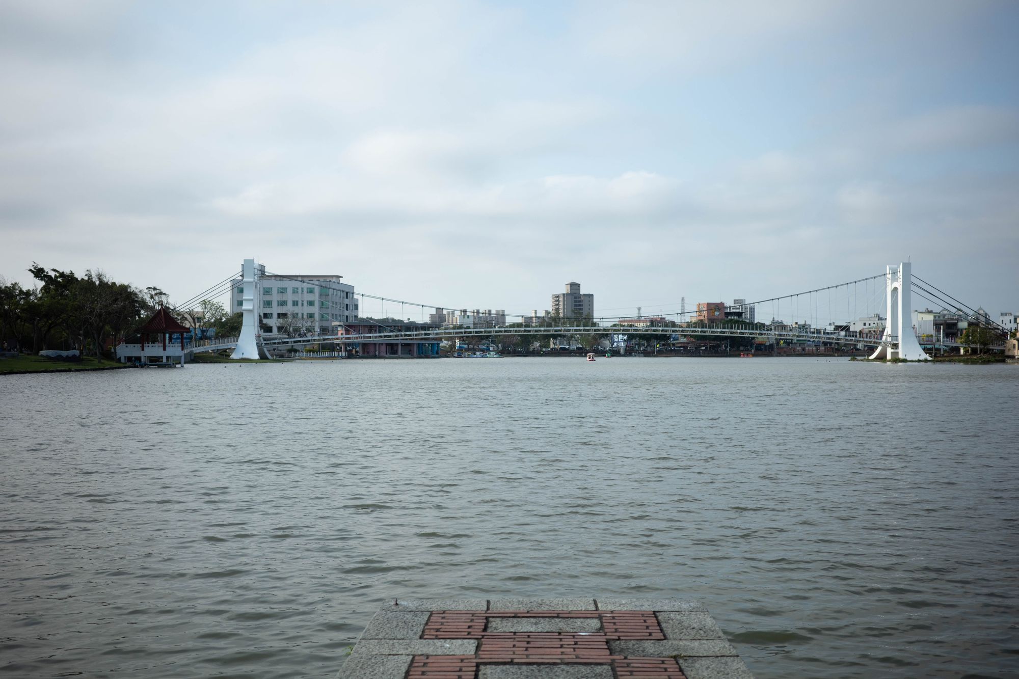 A wide lake with a suspension bridge across the far shore in Taoyuan City.