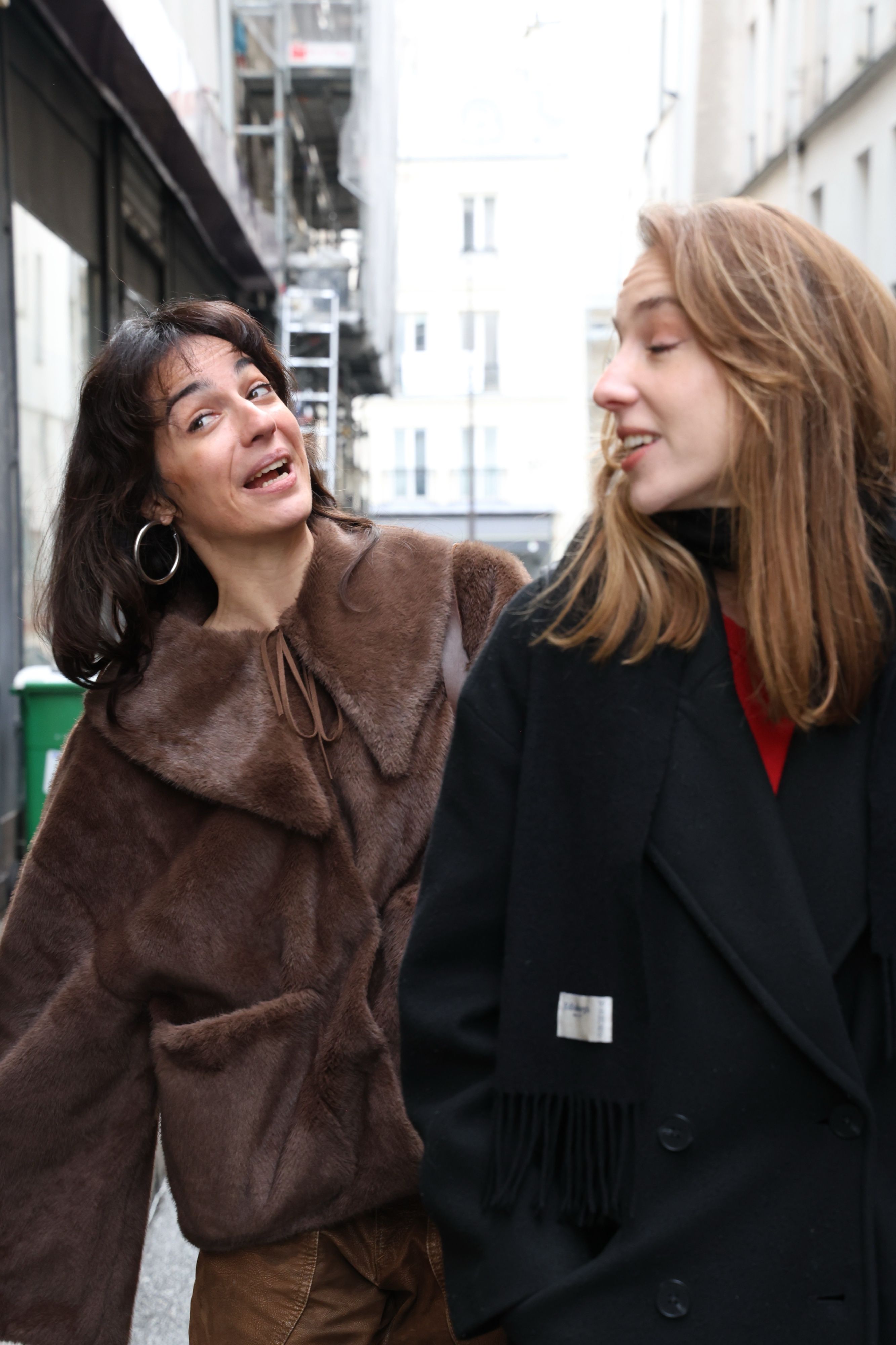 Two women laughing as they walk down a Paris street