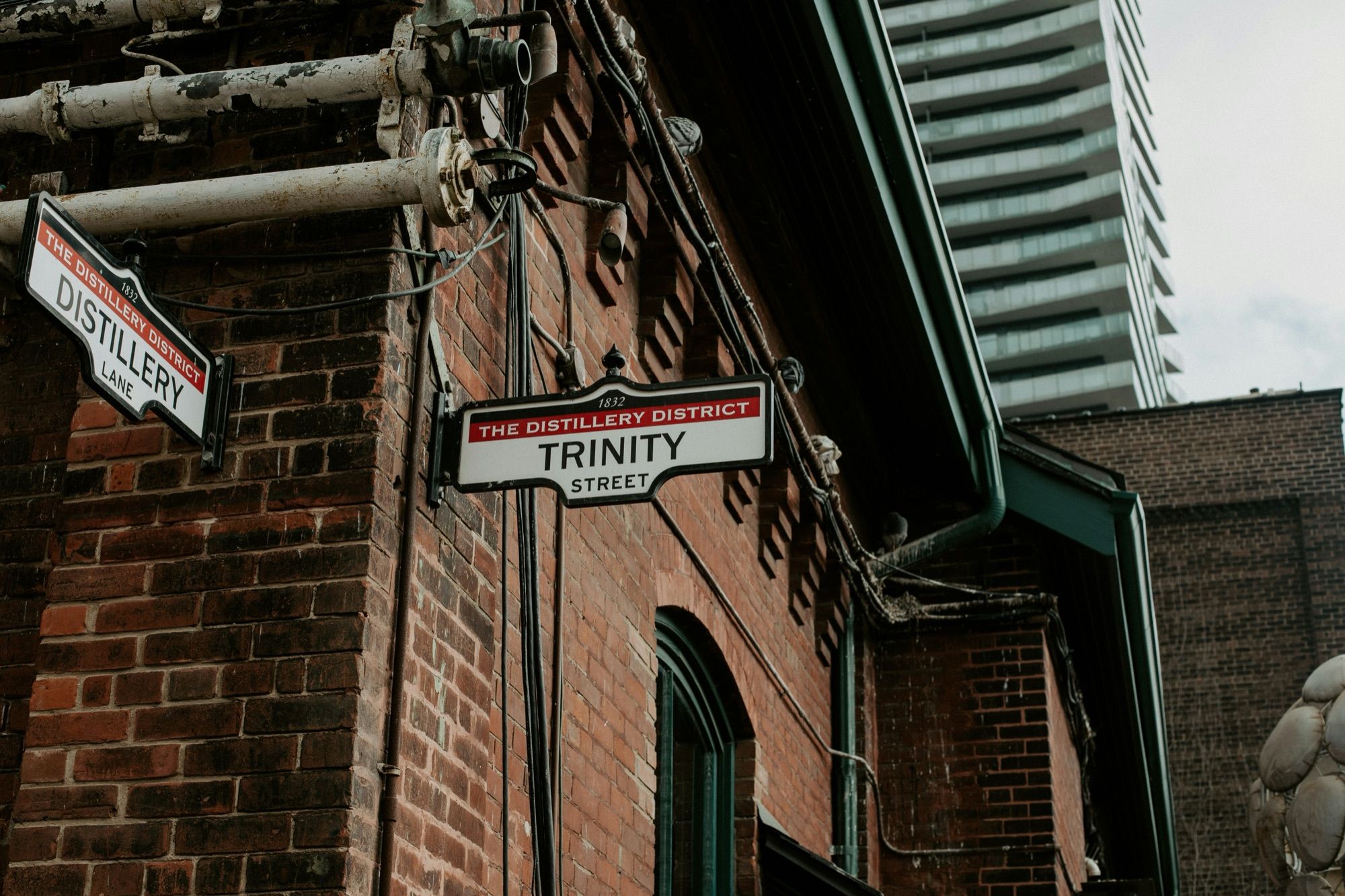 Signs for Distillery Lane and Trinity Street on a brick building in Toronto’s Distillery District