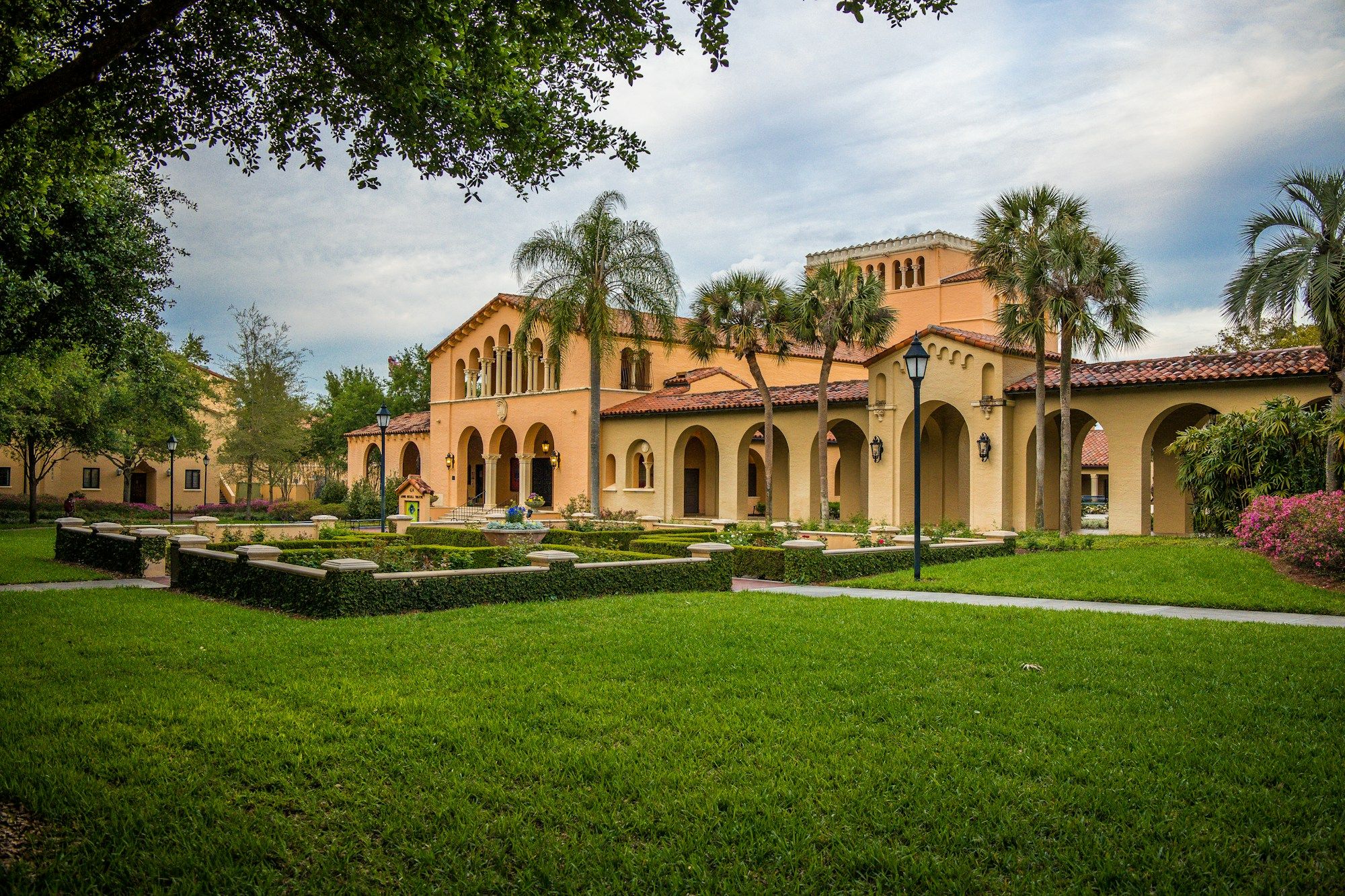 A Spanish-style building with a red tile roof and palm trees, seen across a lawn at Rollins College in Winter Park near Orlando.