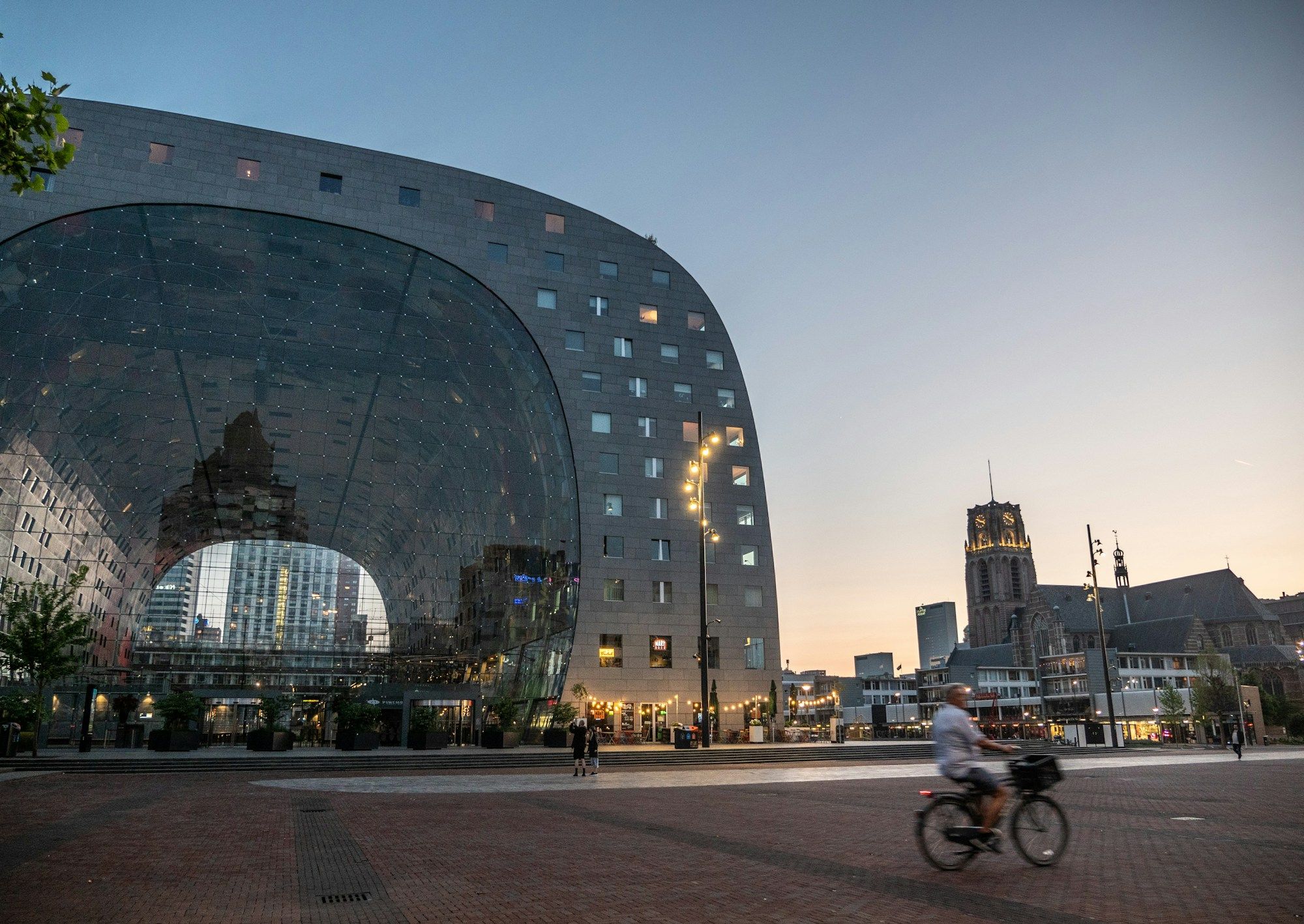 The Markthal in Rotterdam with a cyclist crossing the square at dusk