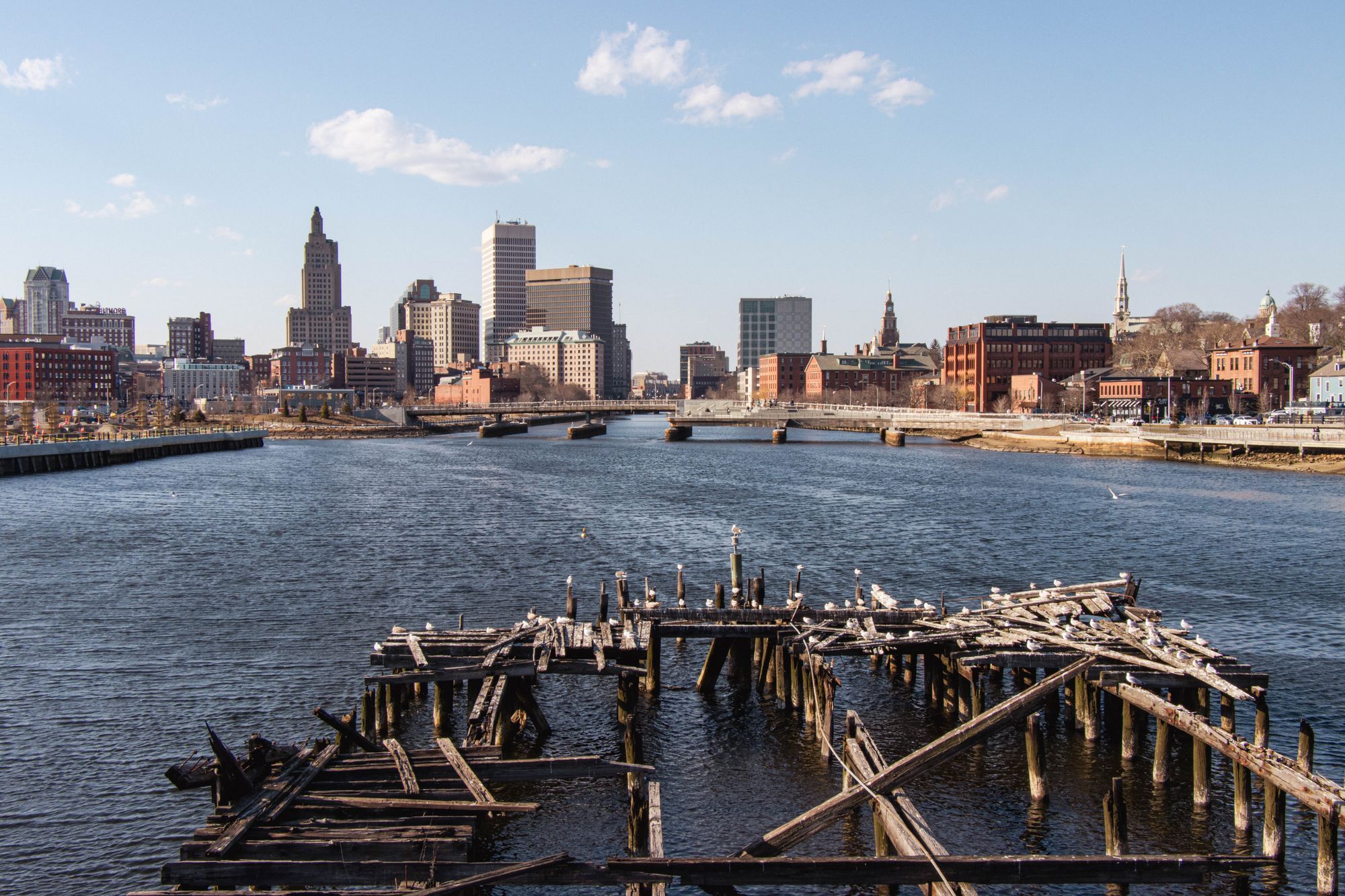 The Providence skyline across the river, with old wooden pilings in the foreground.