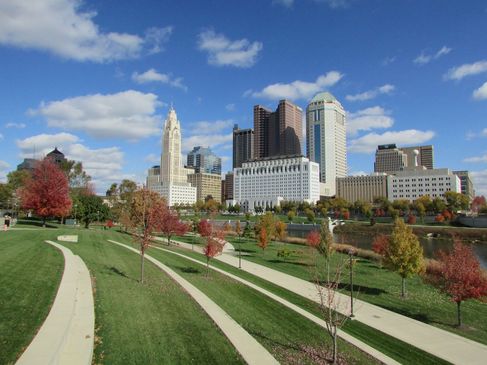 Downtown Columbus with the LeVeque Tower beyond an autumn park and walking paths.