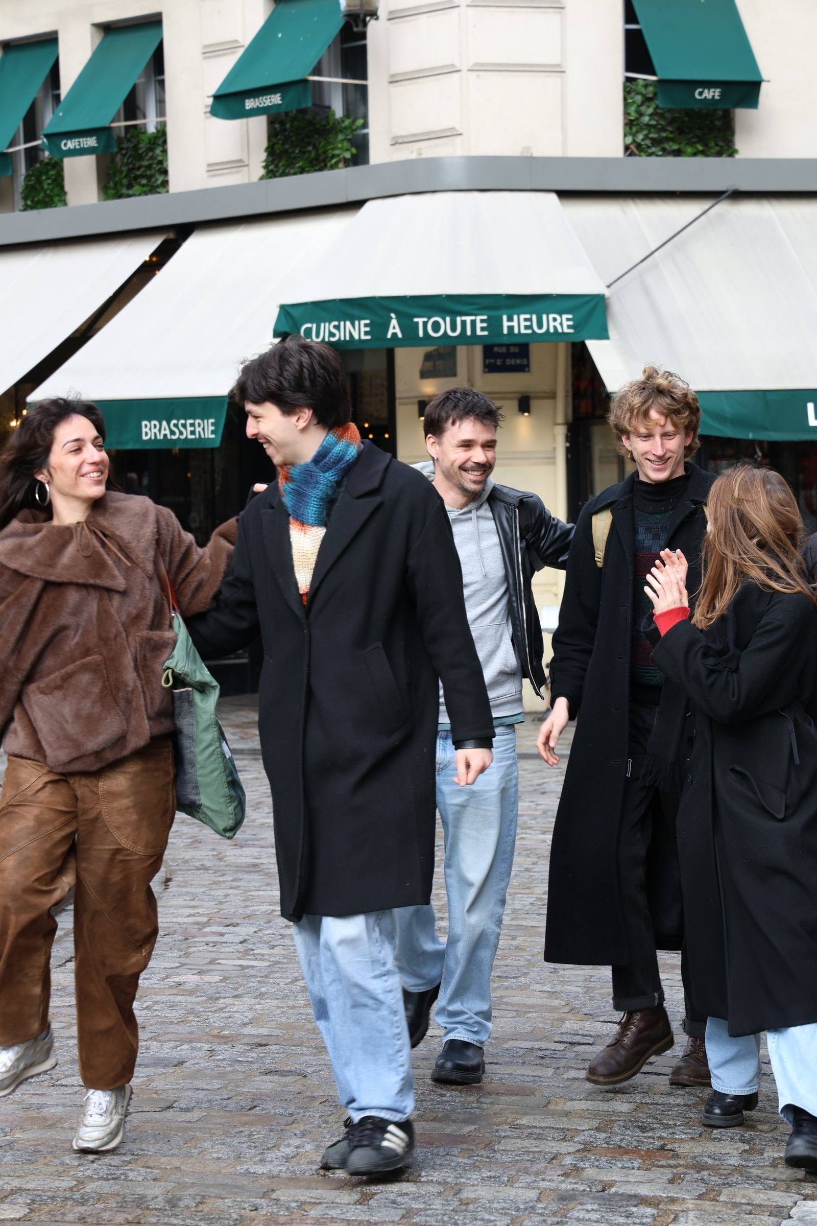 A group crossing a city square past a corner brasserie on a Timeleft walk