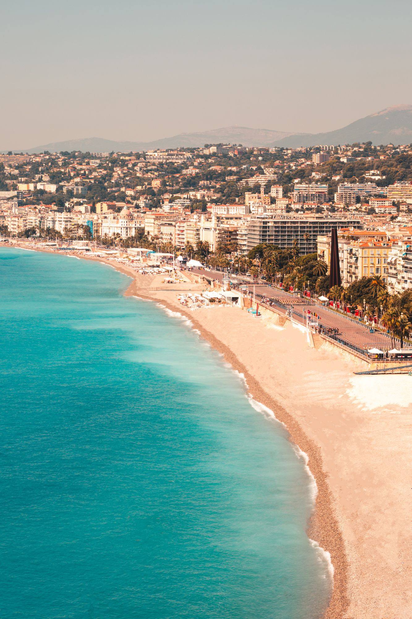 The curve of the Baie des Anges and the Promenade des Anglais in Nice, with turquoise water in front of the seafront buildings.