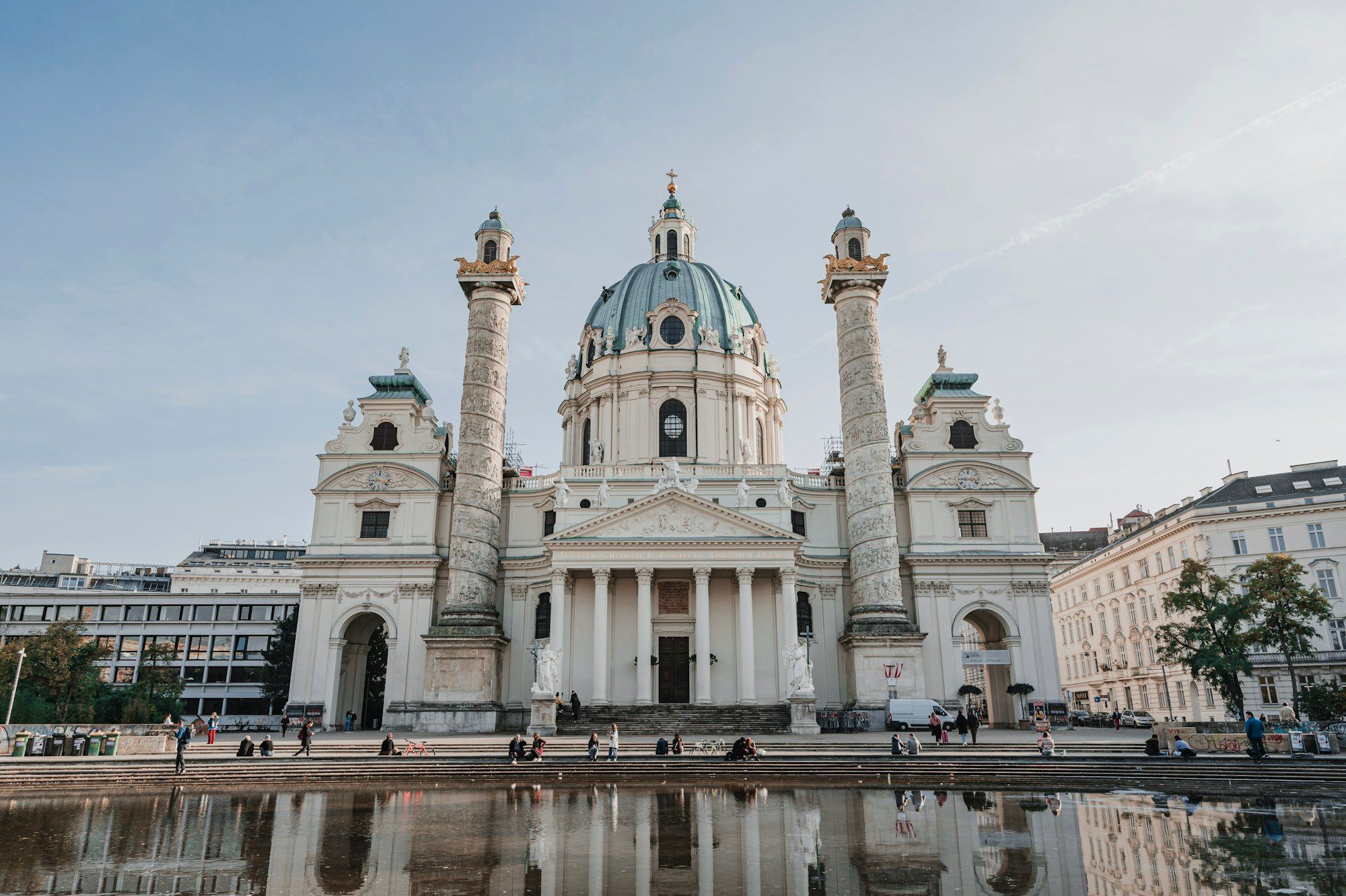 The Karlskirche in Vienna seen across the pond on Karlsplatz, with the church reflected in the water.