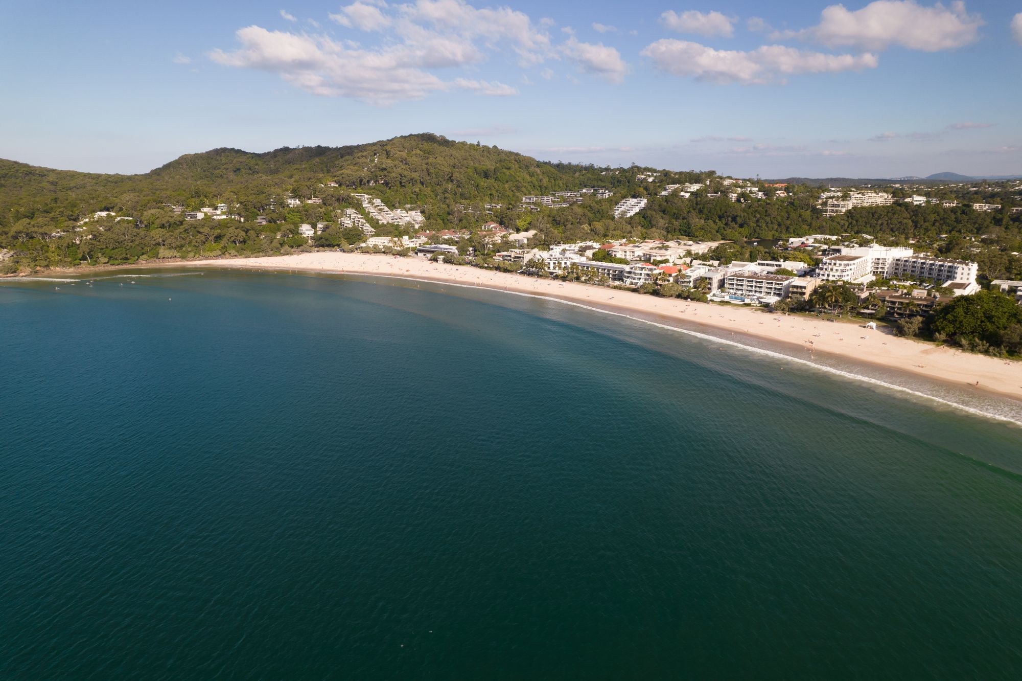 An aerial view of Noosa Main Beach on the Sunshine Coast, with waterfront hotels and surf along the sand.