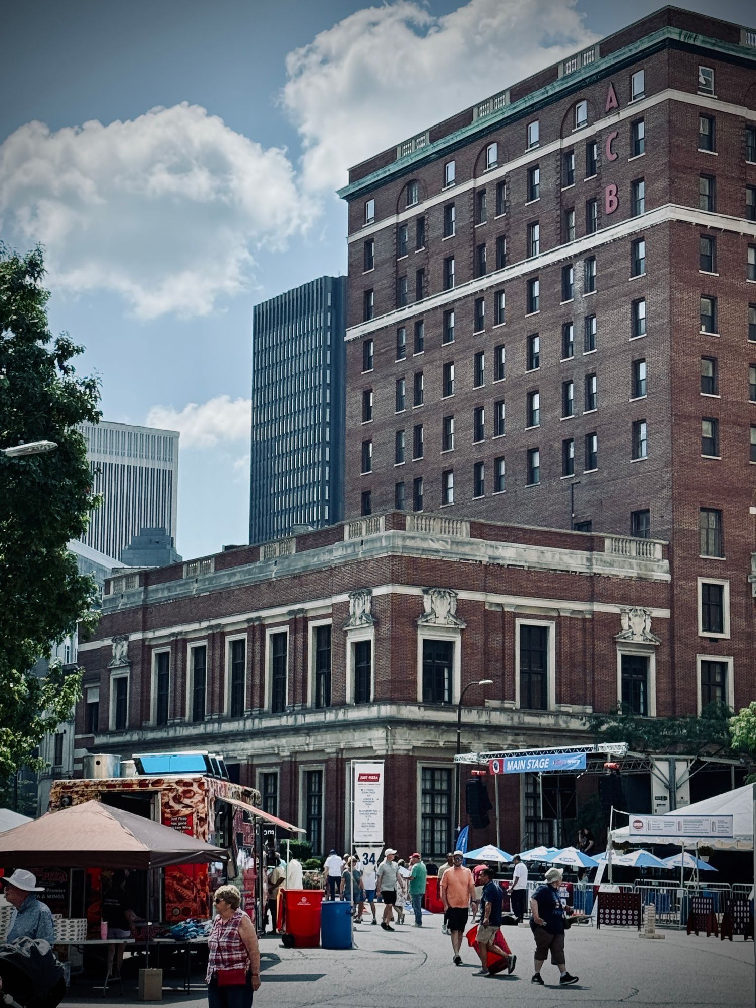 Shoppers at market stalls beside a historic brick building in downtown Buffalo.