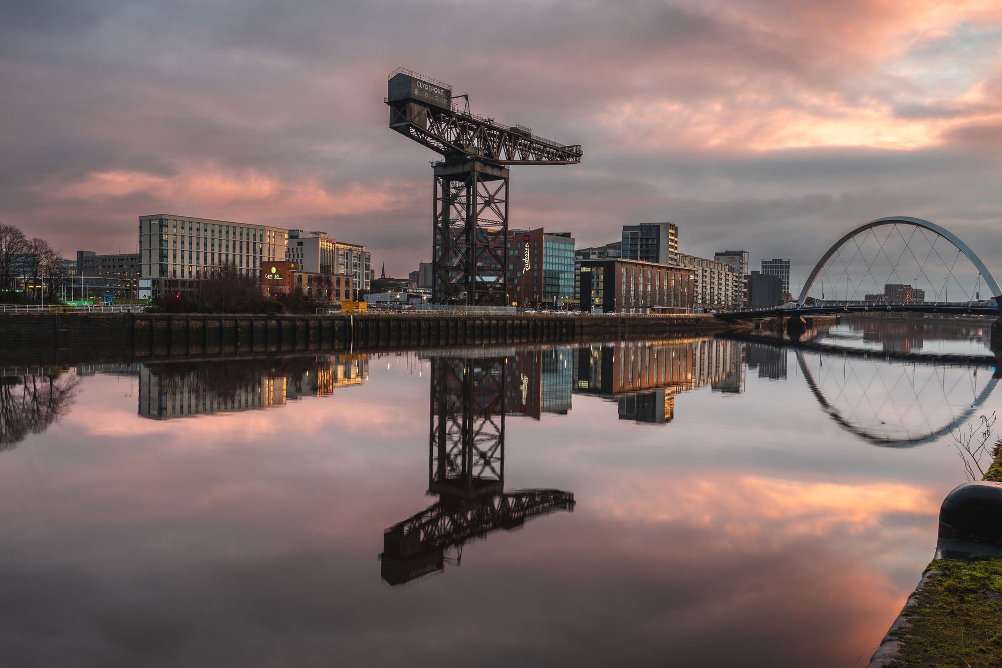 The Finnieston Crane and the Clyde Arc bridge reflected in the River Clyde at sunset in Glasgow.