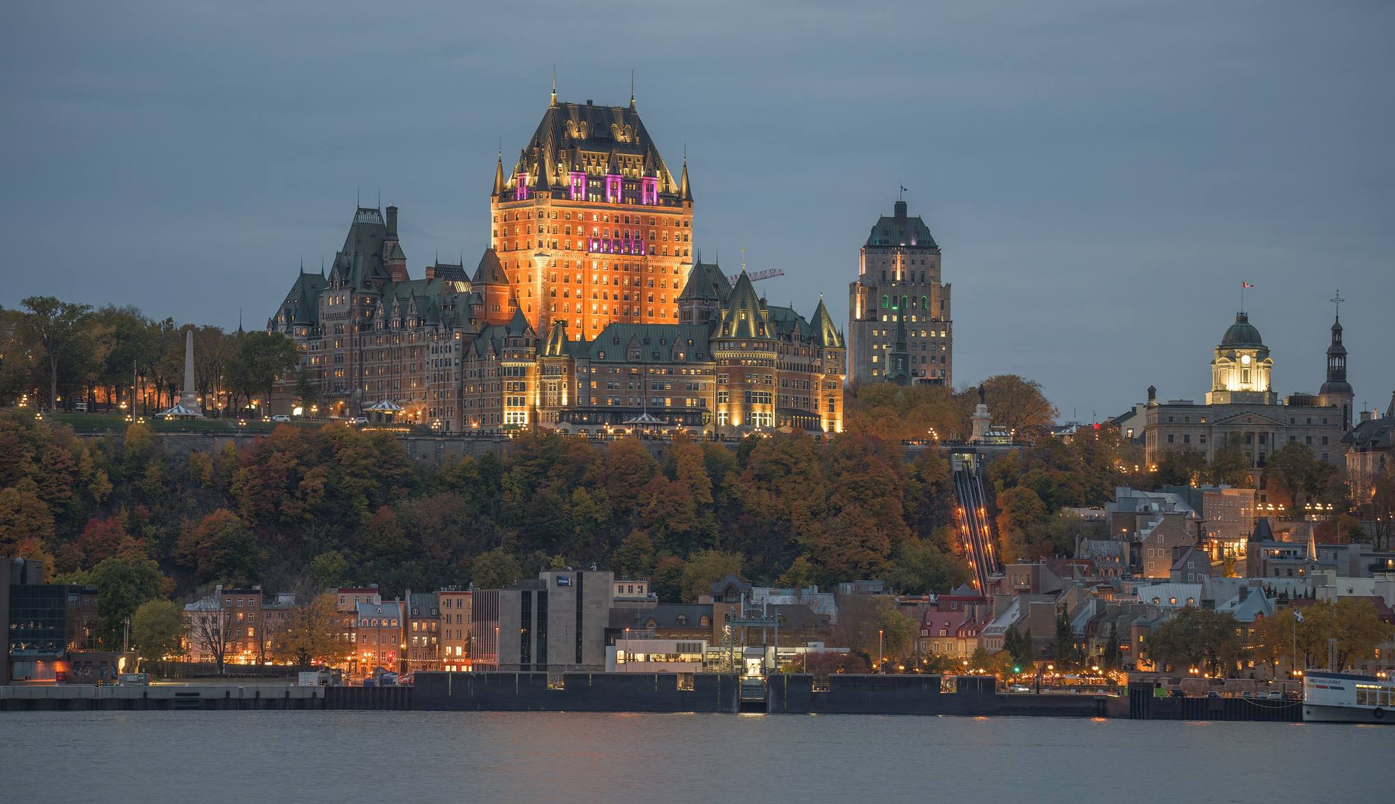 Château Frontenac lit at dusk above the Upper Town of Quebec City, seen from across the St Lawrence River.