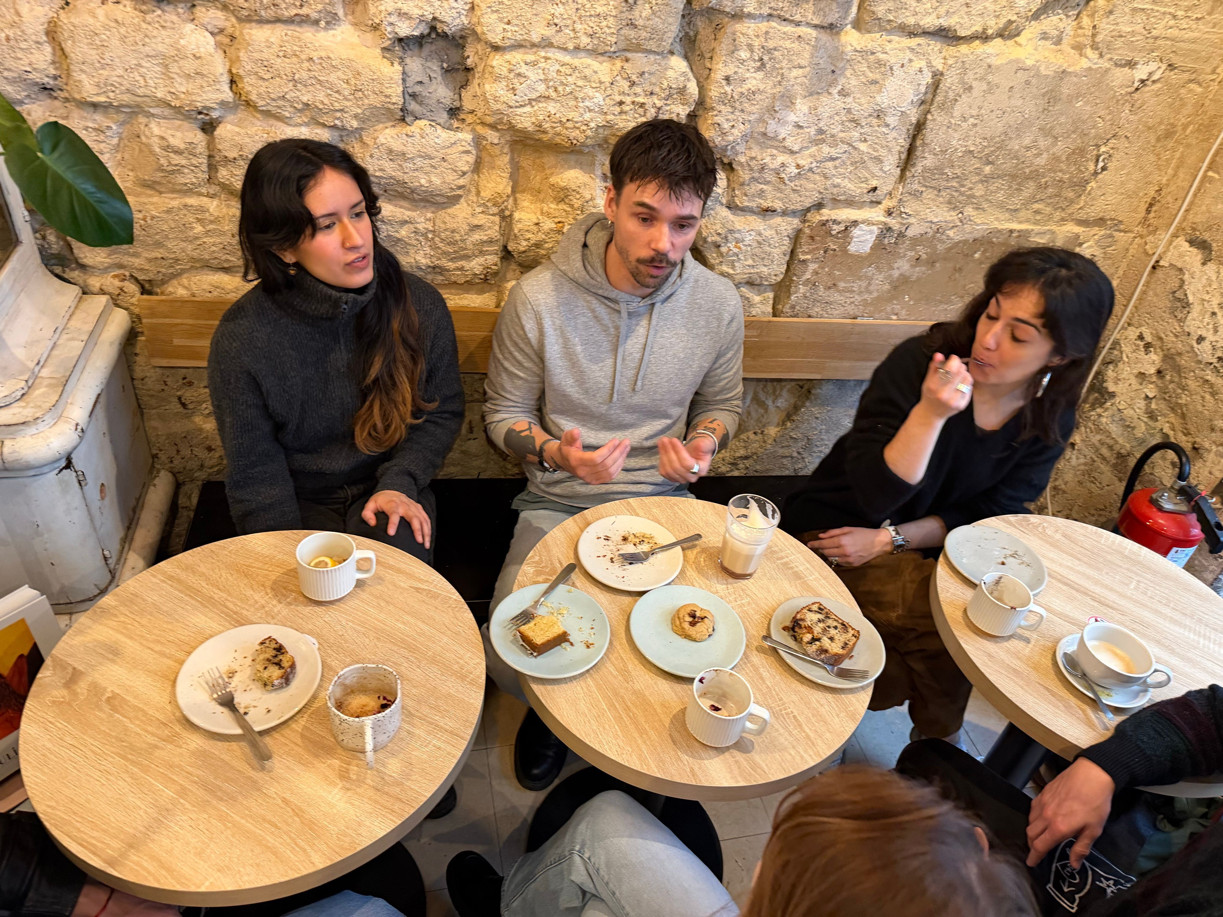 Three people talking over coffee and cake on a café banquette