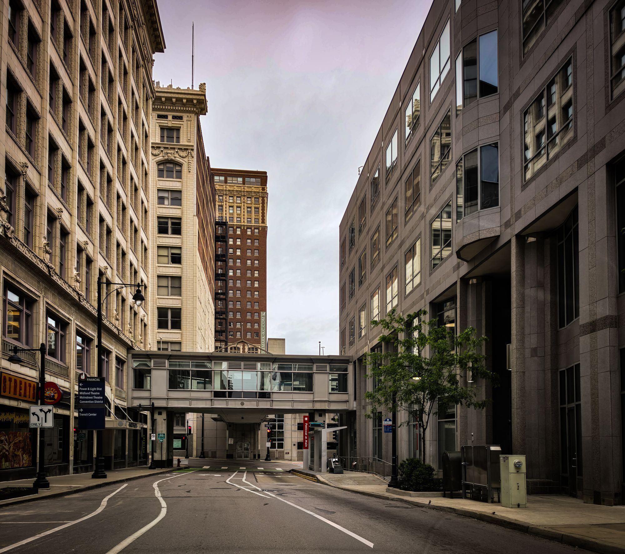 A quiet downtown street in Kansas City, Missouri, with historic buildings and a skywalk over the road.