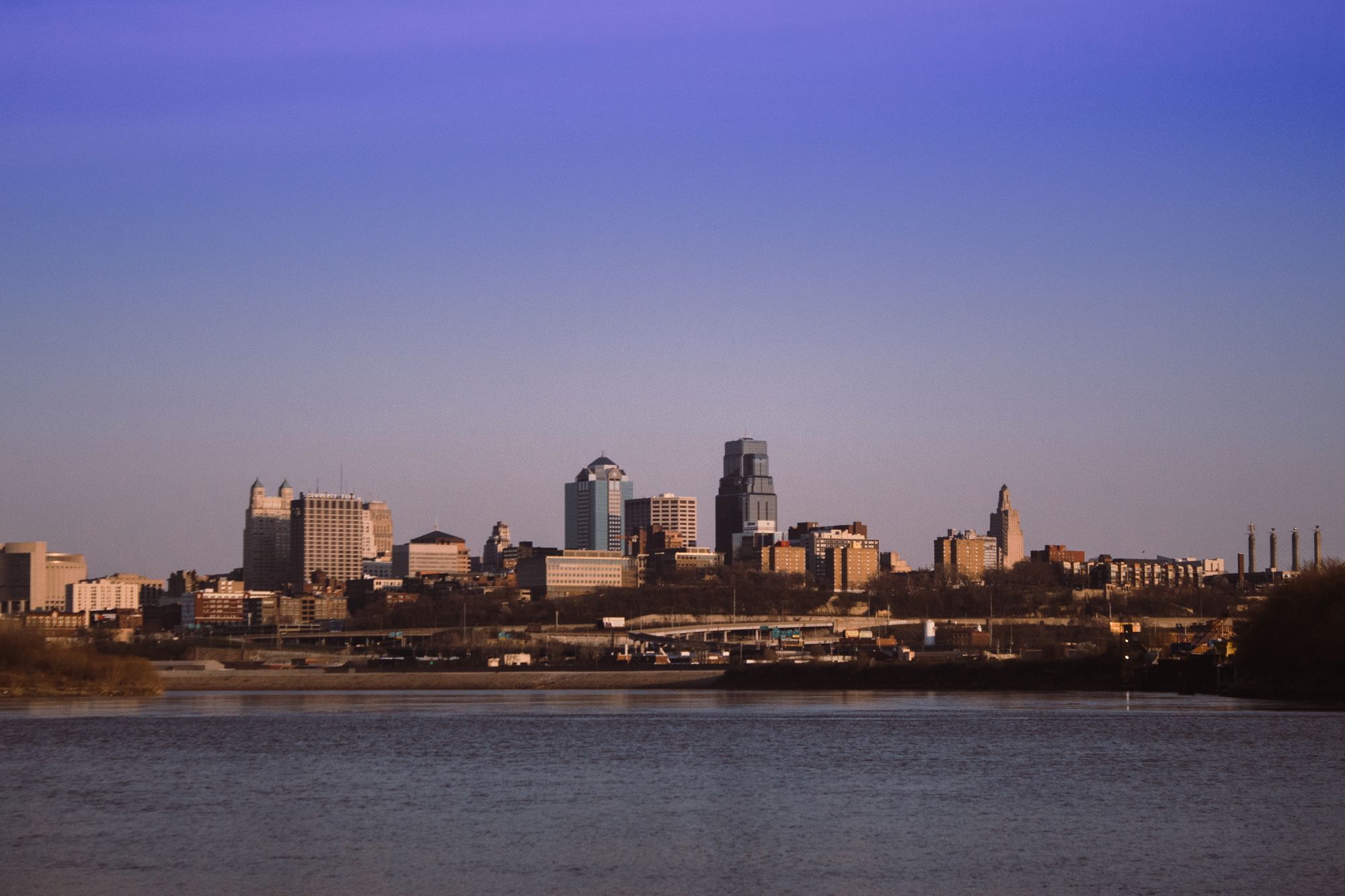 The Kansas City skyline across the Missouri River at dusk.