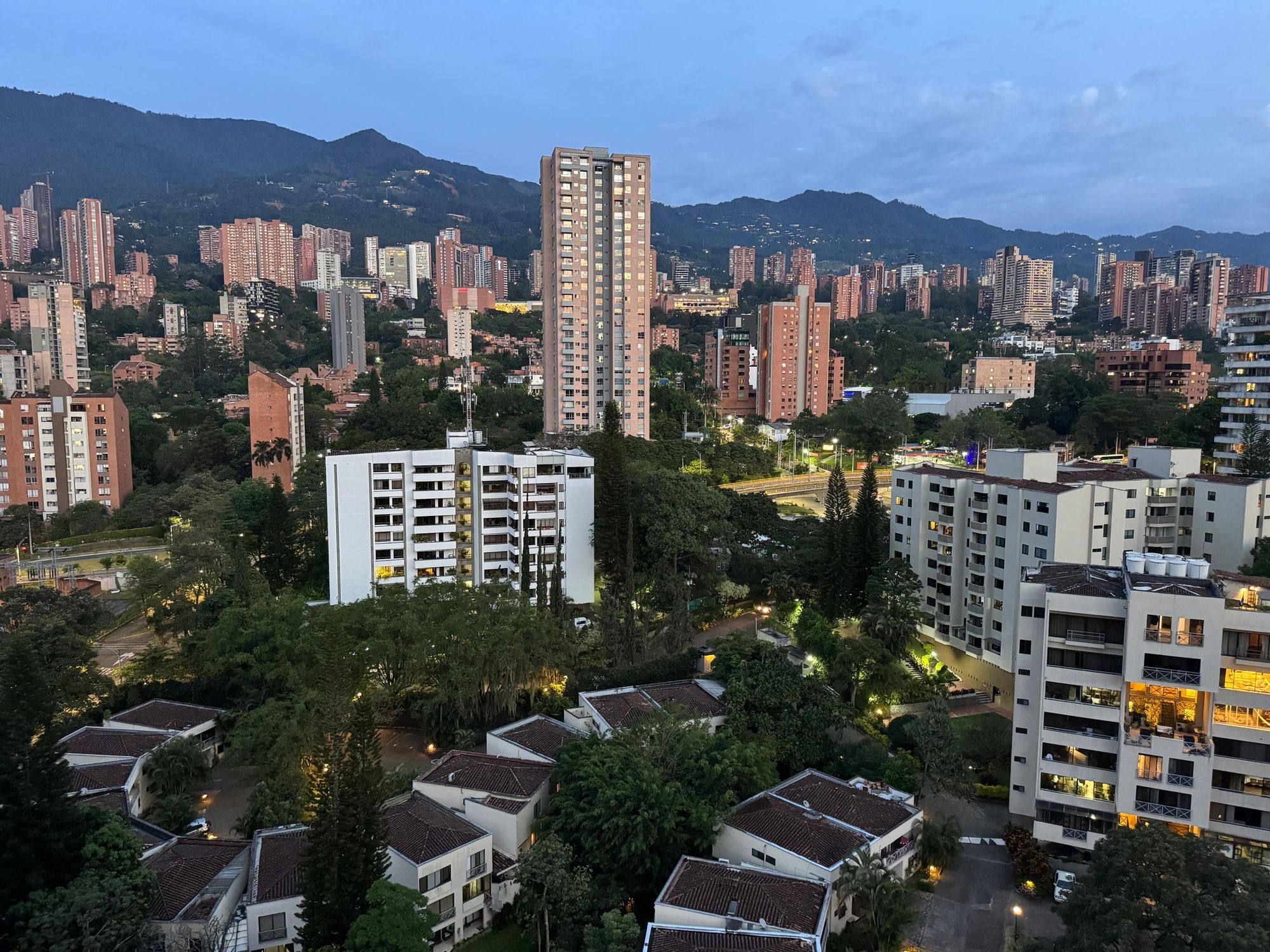 Torres residenciales y laderas verdes de Medellín con los Andes al fondo.