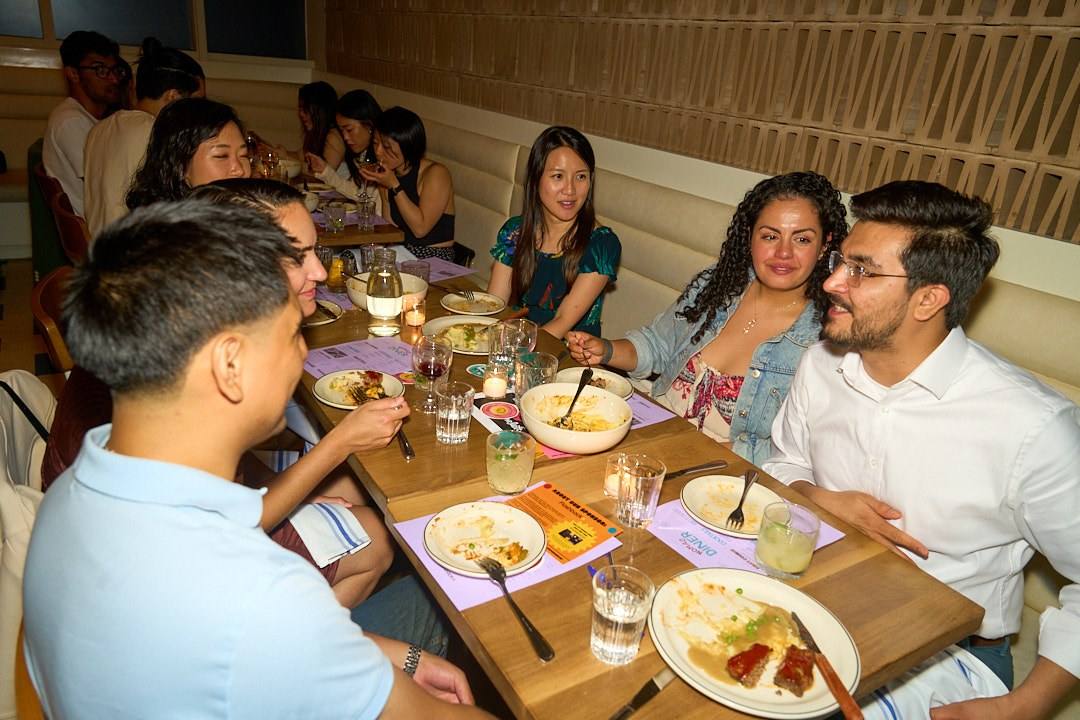 Six guests smiling around a long table at a Timeleft dinner