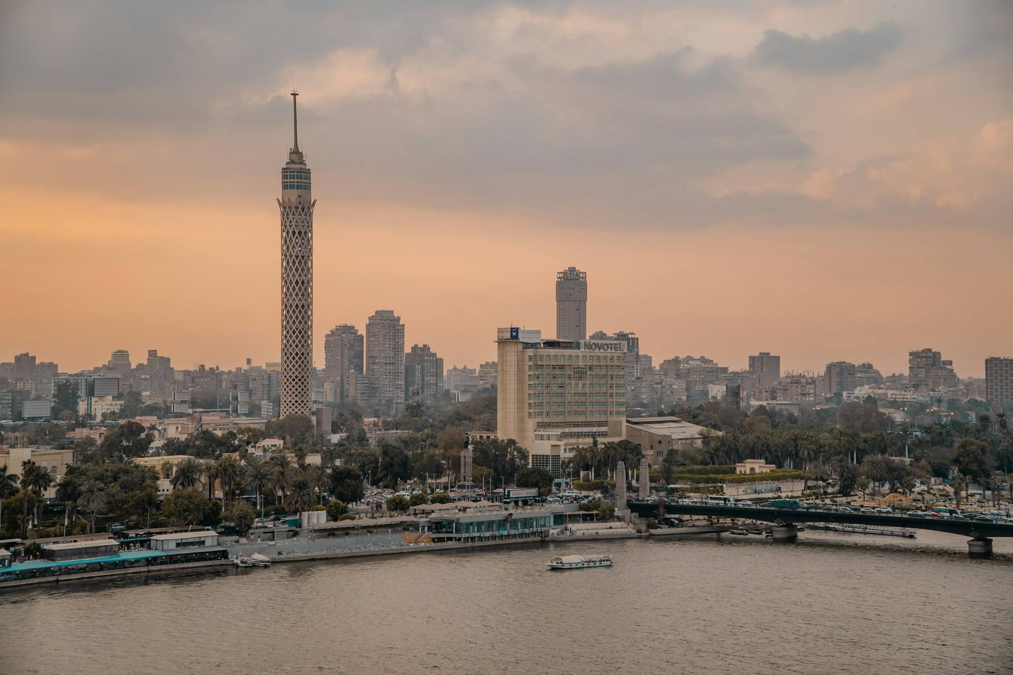 The Cairo Tower rising above the skyline of Cairo beside the Nile, in warm evening light.