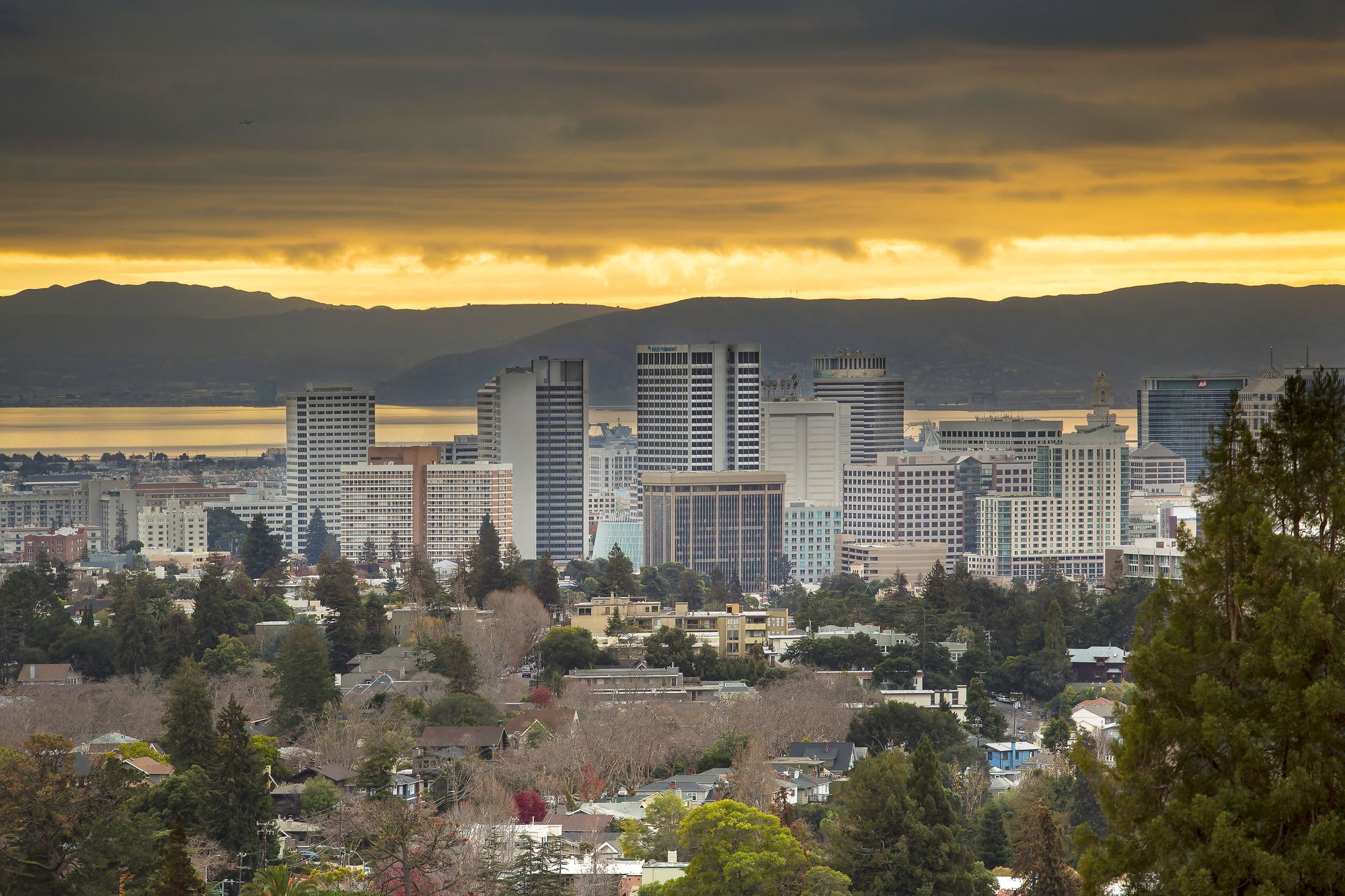 The downtown Oakland skyline under a golden sunset sky.