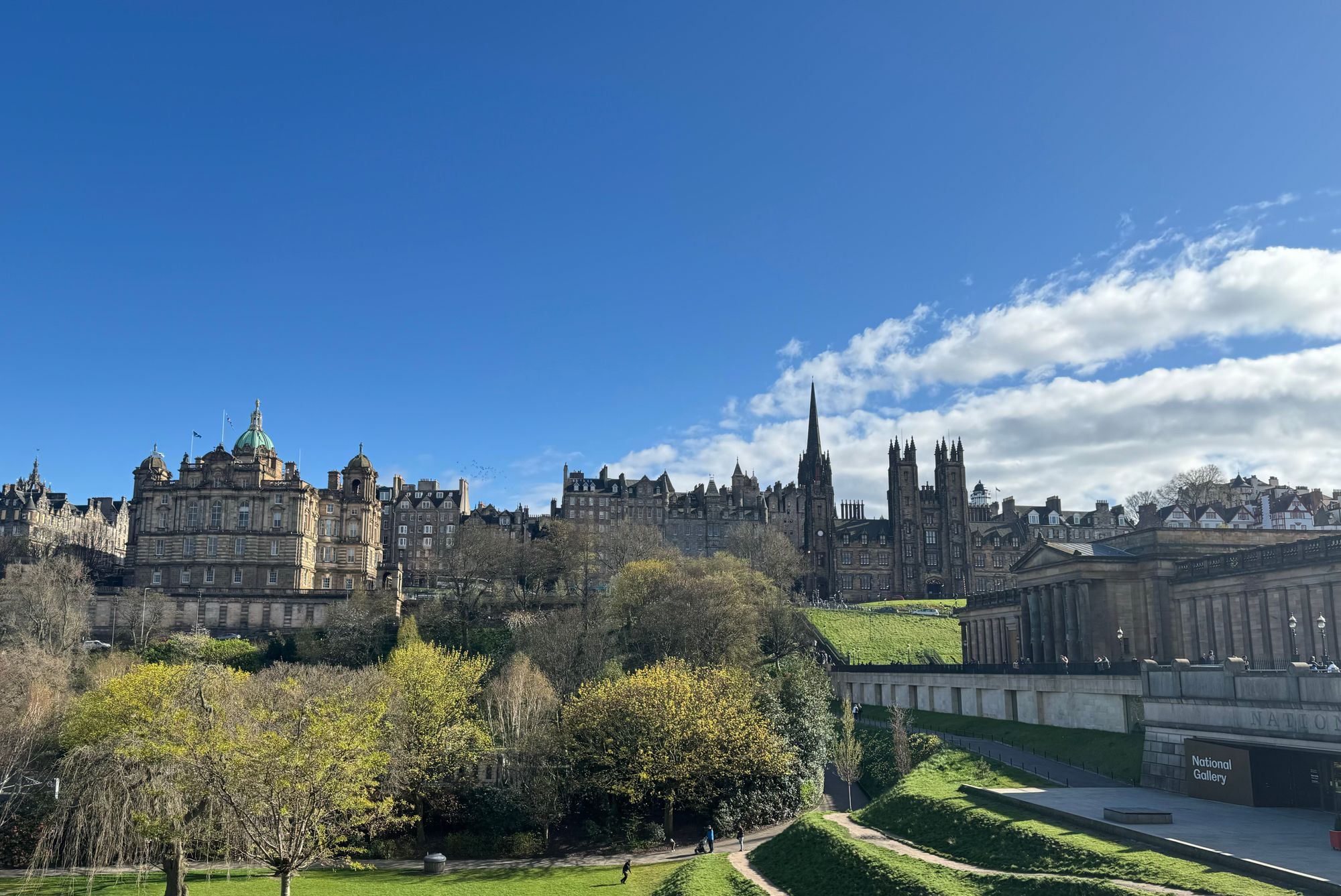 The Old Town skyline of Edinburgh seen across Princes Street Gardens on a sunny day.