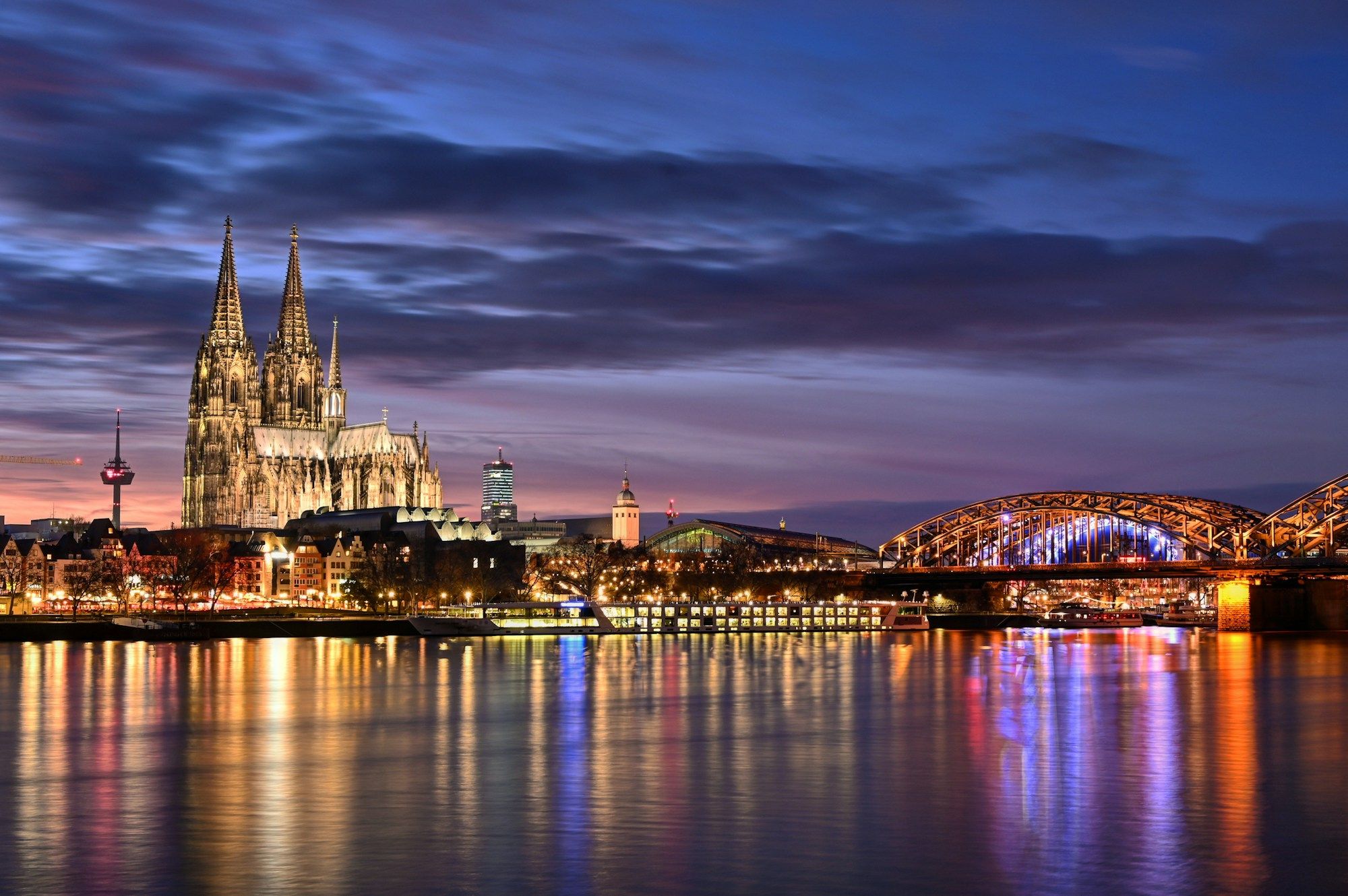 Cologne Cathedral and the Hohenzollern Bridge reflected in the Rhine at dusk
