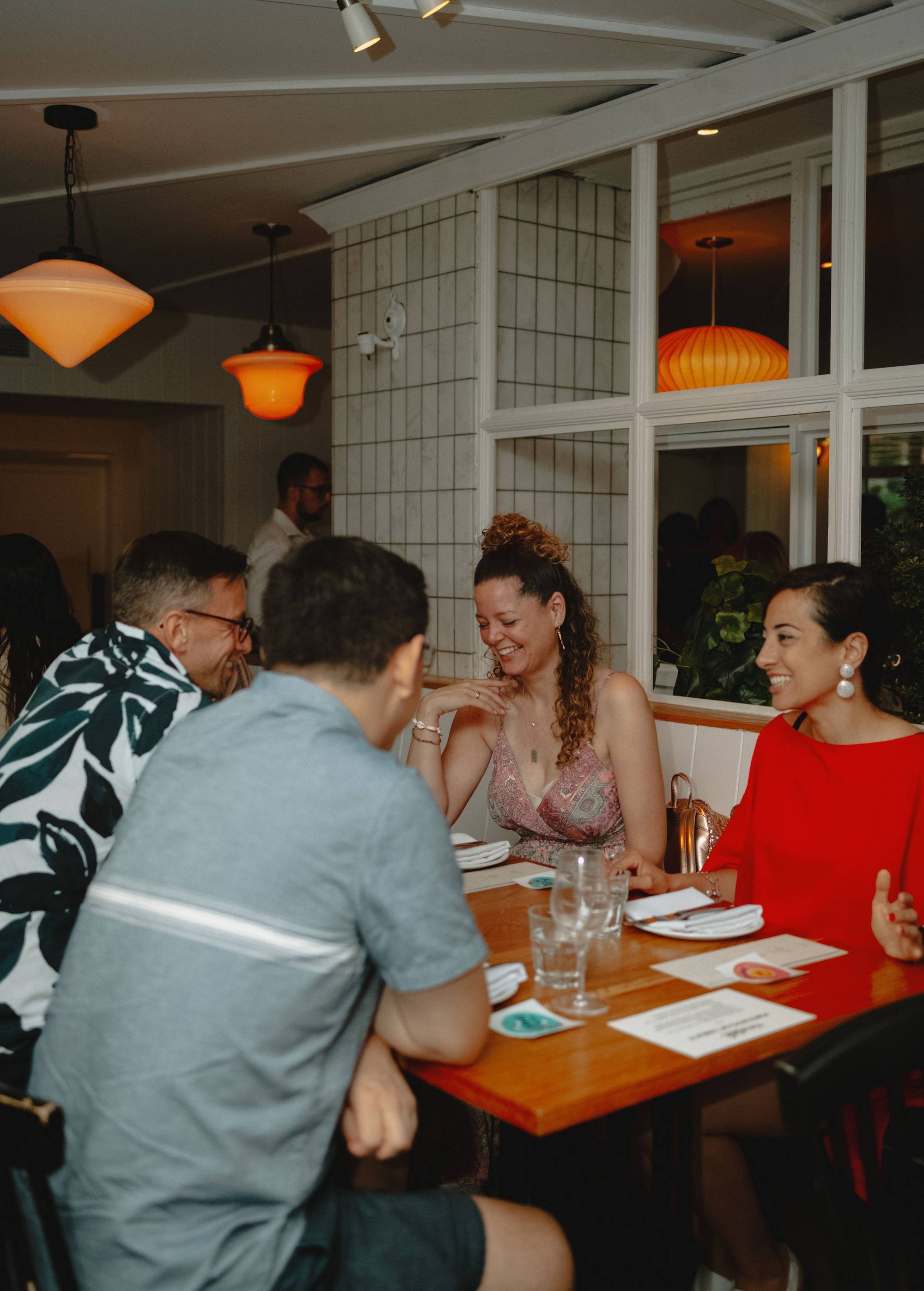 Four people laughing together at a window table during a Timeleft dinner