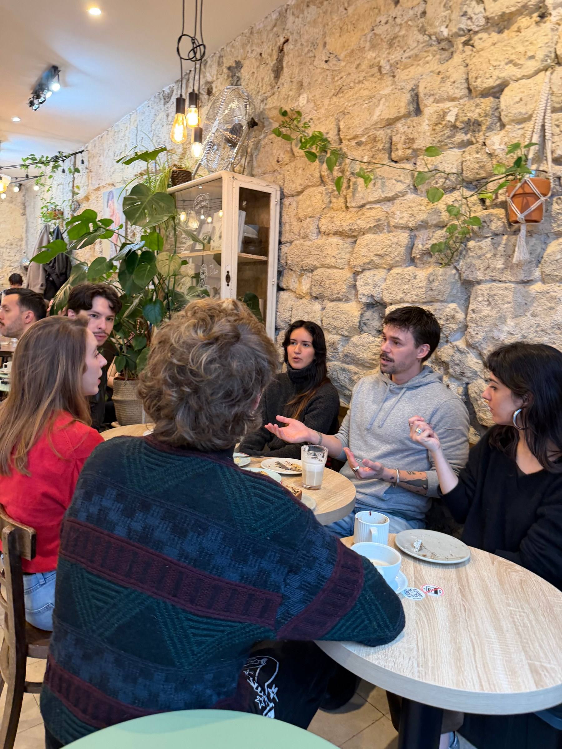 Six people around café tables with plants at a Timeleft coffee