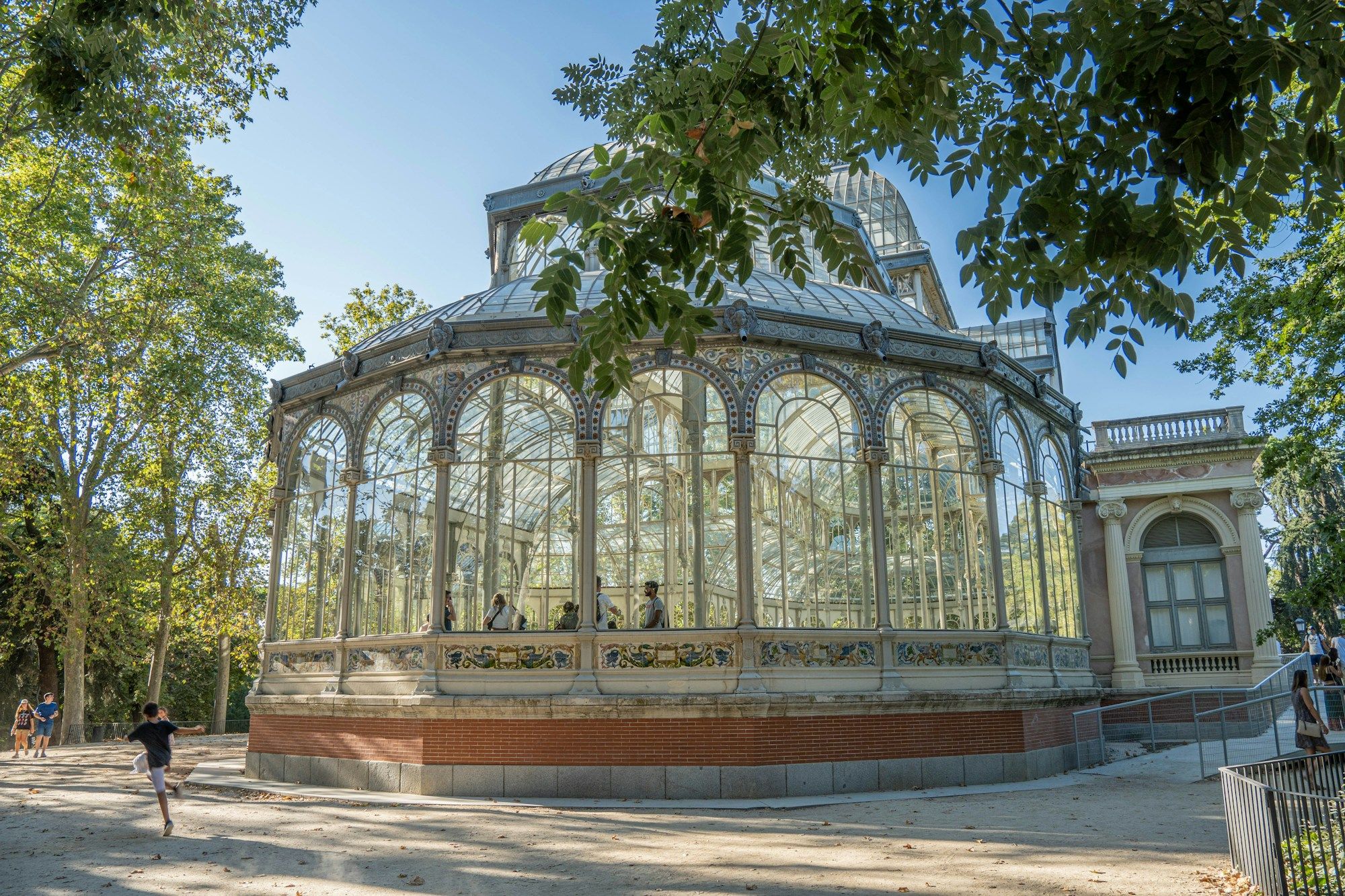 The Palacio de Cristal, a glass and iron pavilion among trees in Retiro Park, Madrid.